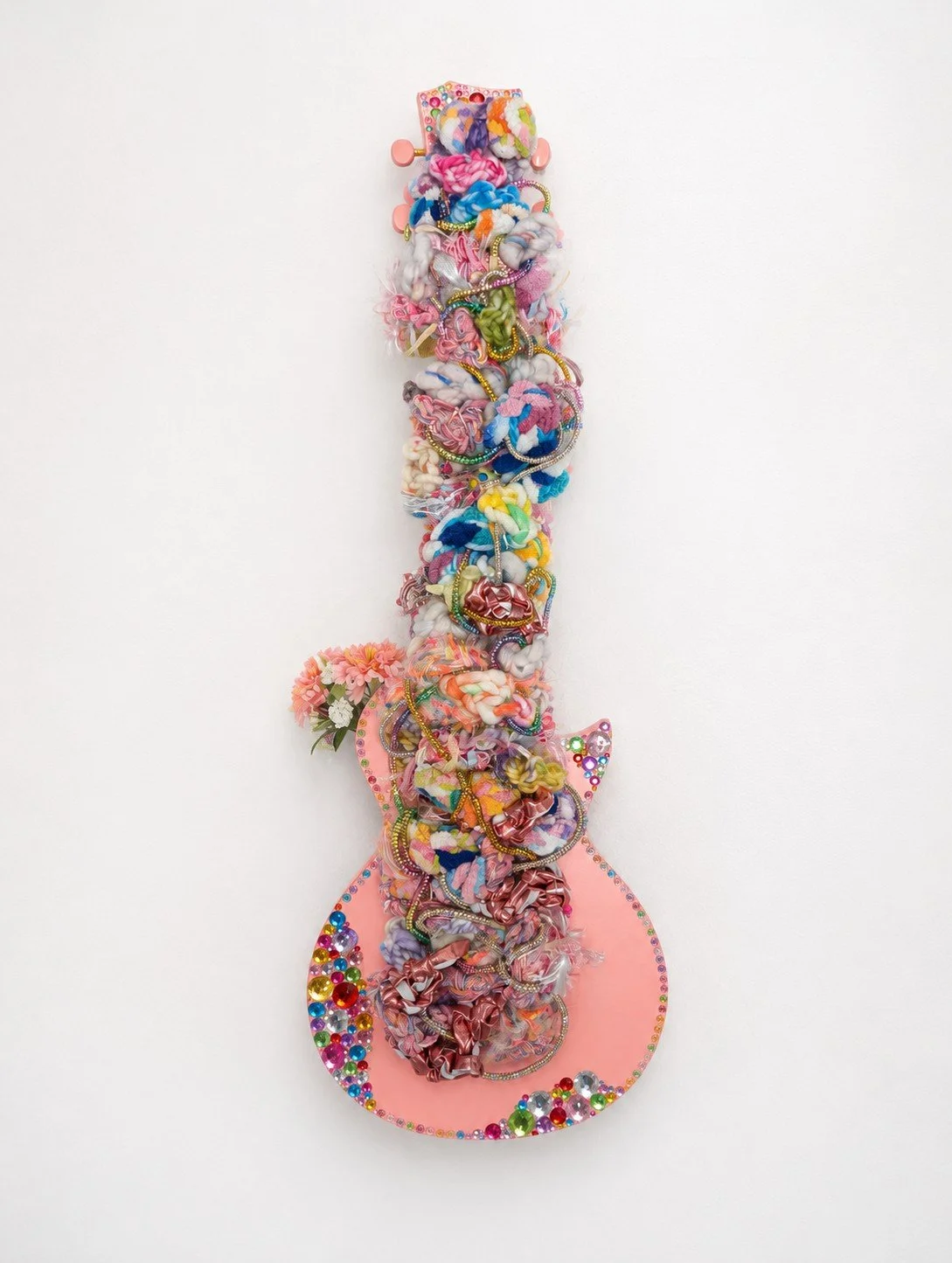 A fiber art piece comprised of interwoven fibers set within the strings of a ukulele, accented with applied rhinestones