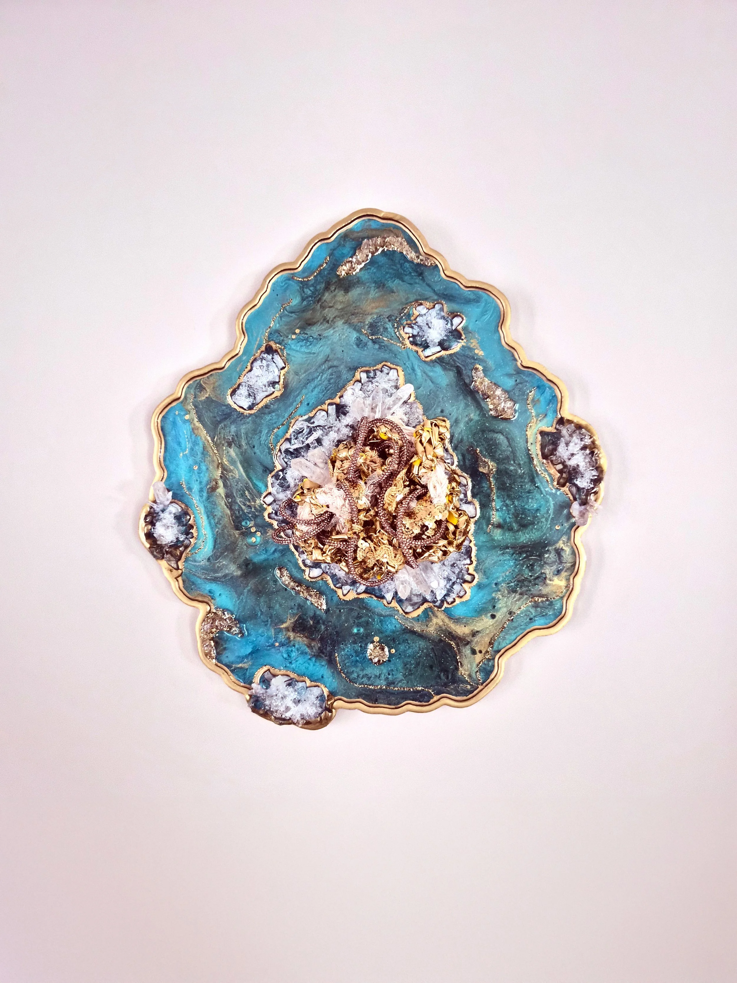 A fiber art piece comprised of interwoven fibers embedded in a resin geode with quartz, crushed glass, fire glass, mica powders, and glitter (resin geode by Emily Goff)
