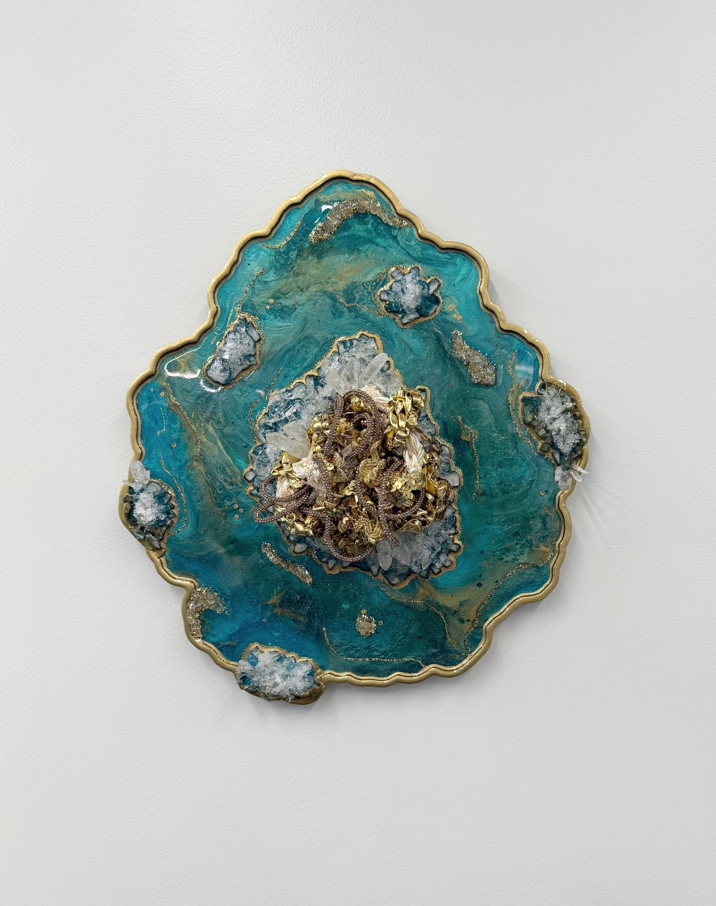 A fiber art piece comprised of interwoven fibers embedded in a resin geode with quartz, crushed glass, fire glass, mica powders, and glitter (resin geode by Emily Goff)