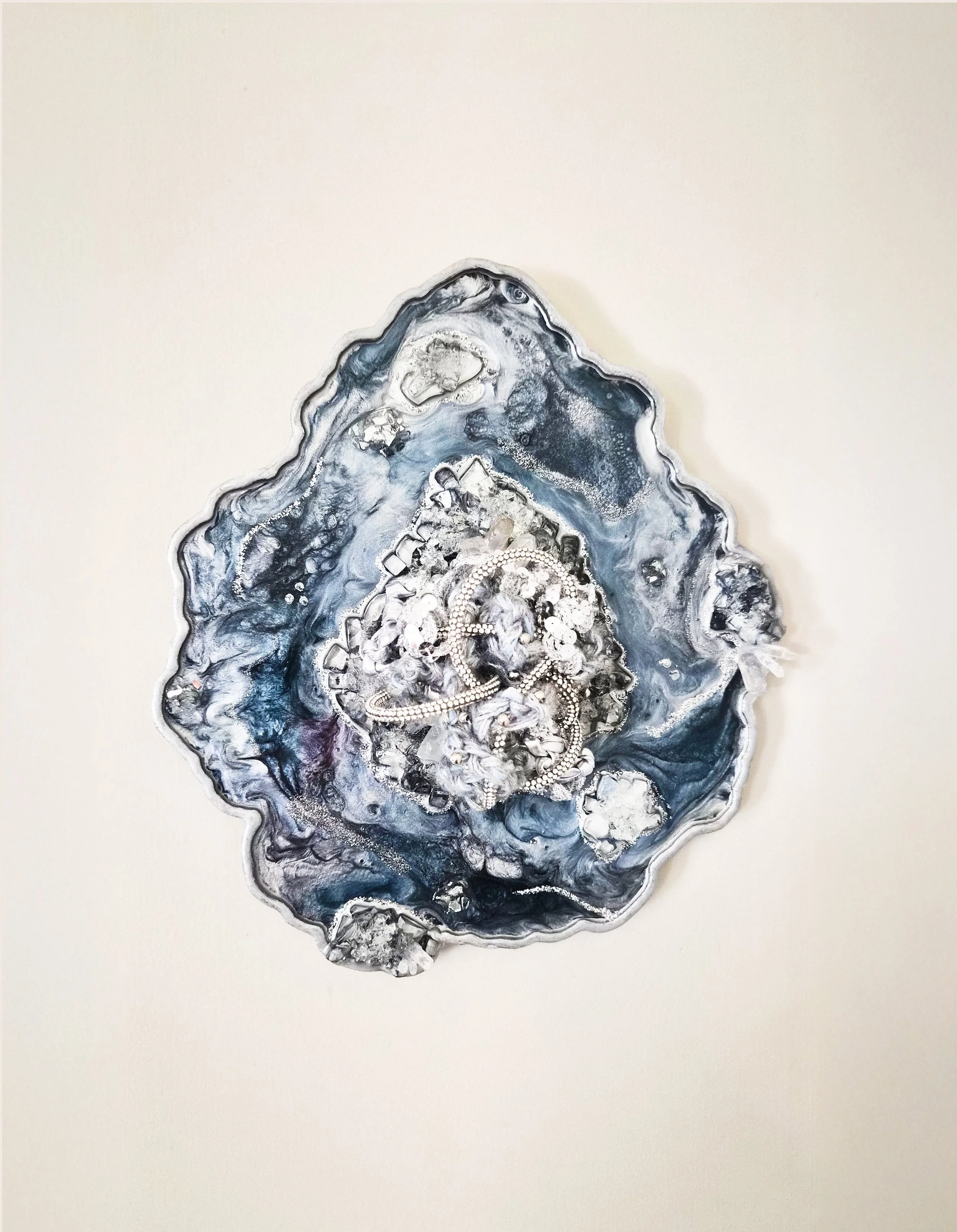 A fiber art piece comprised of interwoven fibers embedded in a resin geode with quartz, crushed glass, fire glass, mica powders, and glitter (resin geode by Emily Goff)