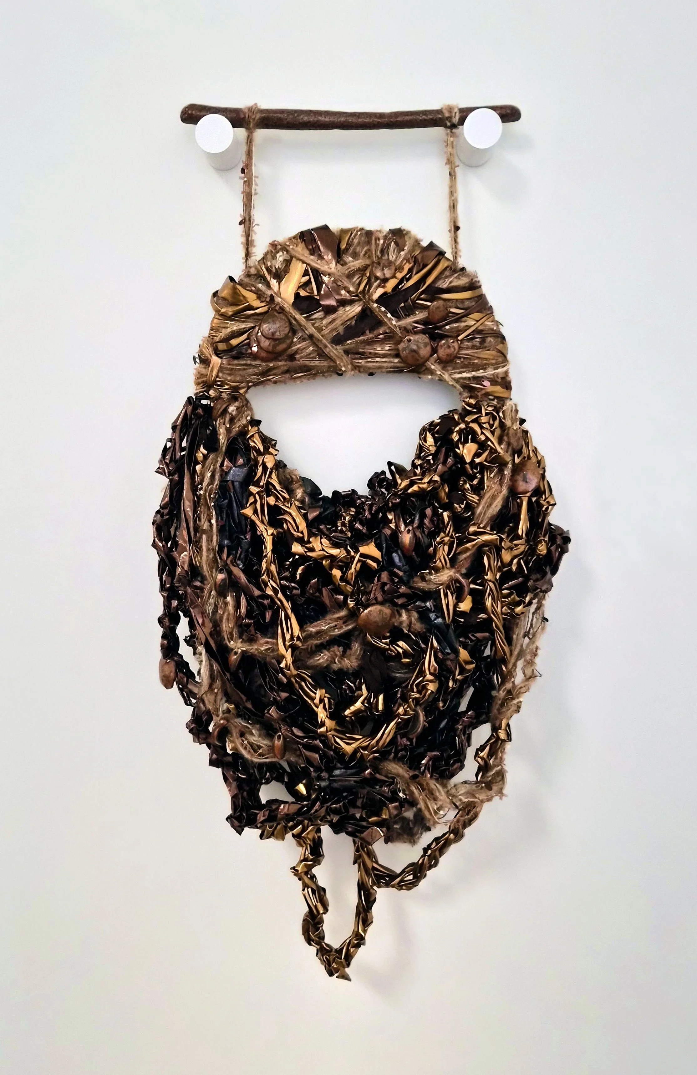 A fiber art piece comprised of interwoven fibers and ceramic beads suspended from a ceramic dowel (ceramic dowel and beads by Tracy Kepley)