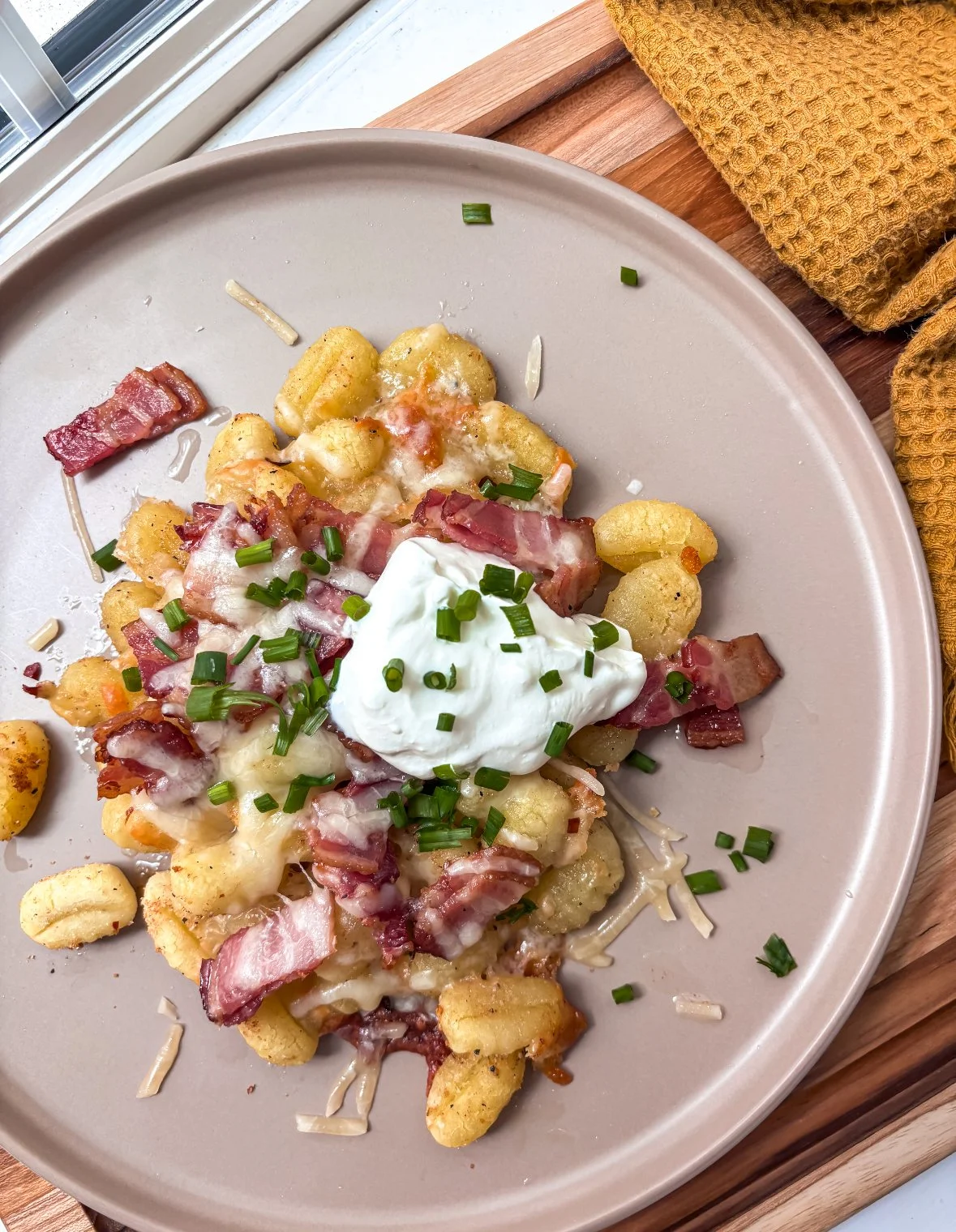 Served plate of breakfast casserole with potatoes, bacon, cheese, sour cream, and chopped green onions.
