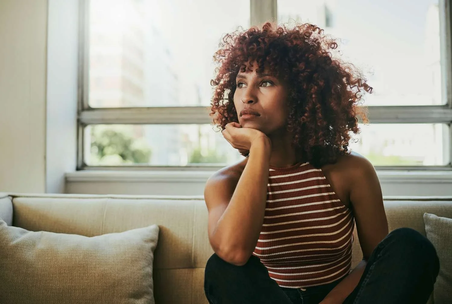 Woman sitting by a window in a thoughtful moment.