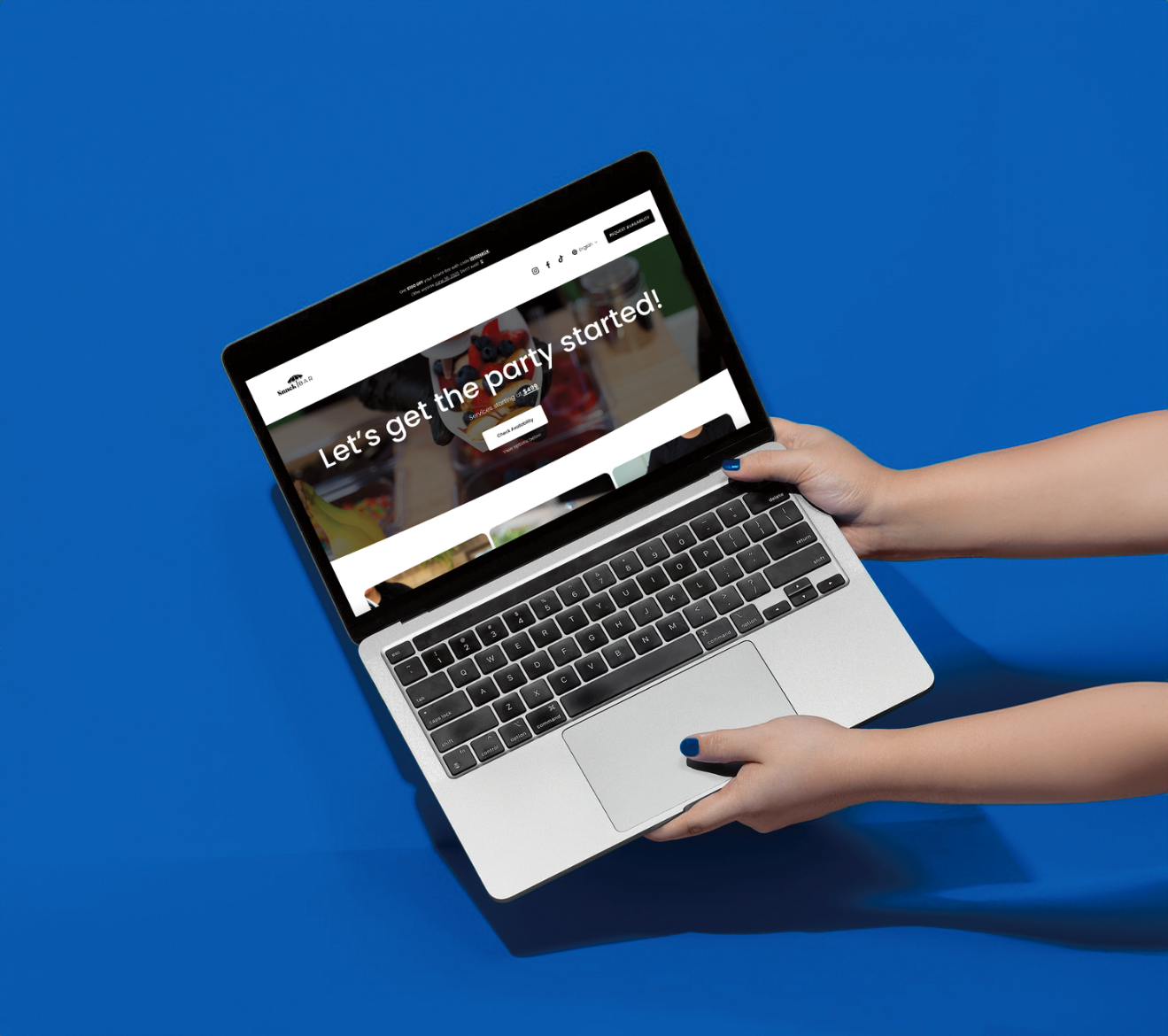 Person holding a silver laptop with a black keyboard against a blue background. The laptop screen displays a website with the text "Let's get the party started!" and a call-to-action button.