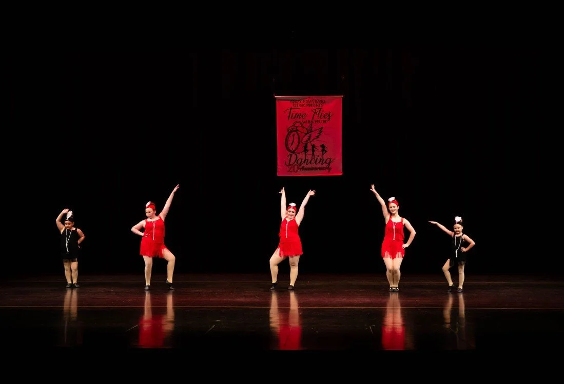 Young dancers performing on stage during a Crazy Moves Dance recital, wearing coordinated costumes under colorful stage lighting..jpg