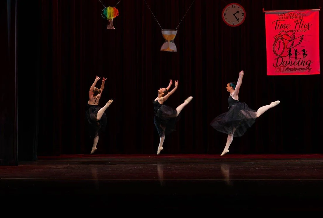 Young dancer performing a solo on stage at a Crazy Moves Dance recital, wearing a vibrant red and black costume under spotlight lighting..jpg