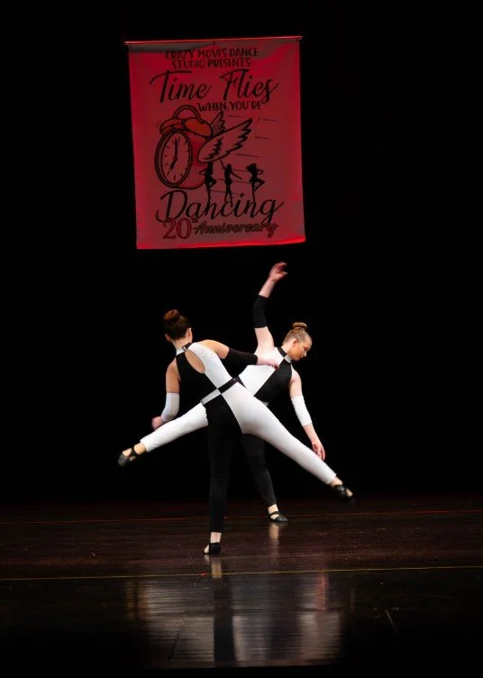 Group of young dancers smiling on stage at a Crazy Moves Dance recital, wearing pink and black costumes after completing their performance..jpg