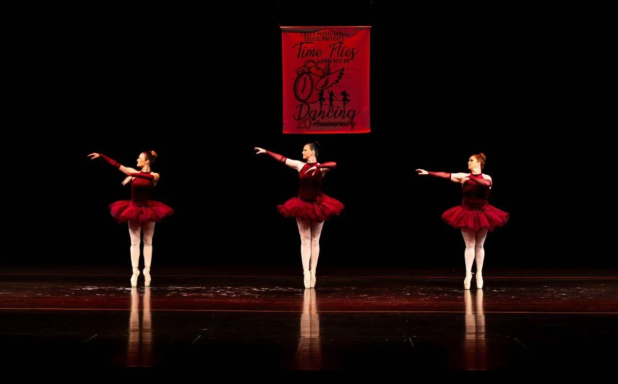 Three ballet dancers in matching maroon tutus performing on stage during Crazy Moves Dance Studio’s 20th anniversary recital under a “Time Flies” banner..jpg