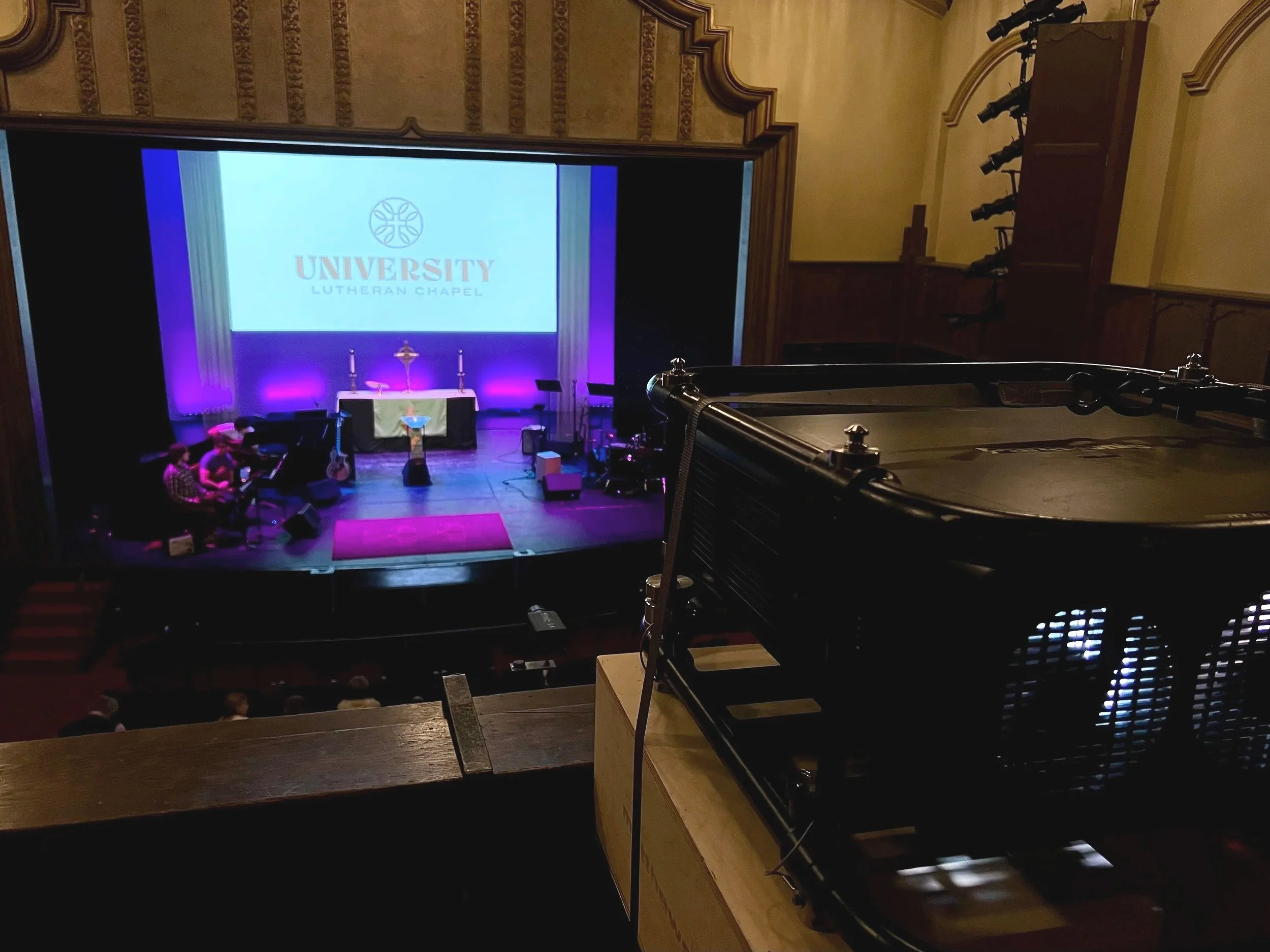 A large video projector displays an image on the back wall of a stage.