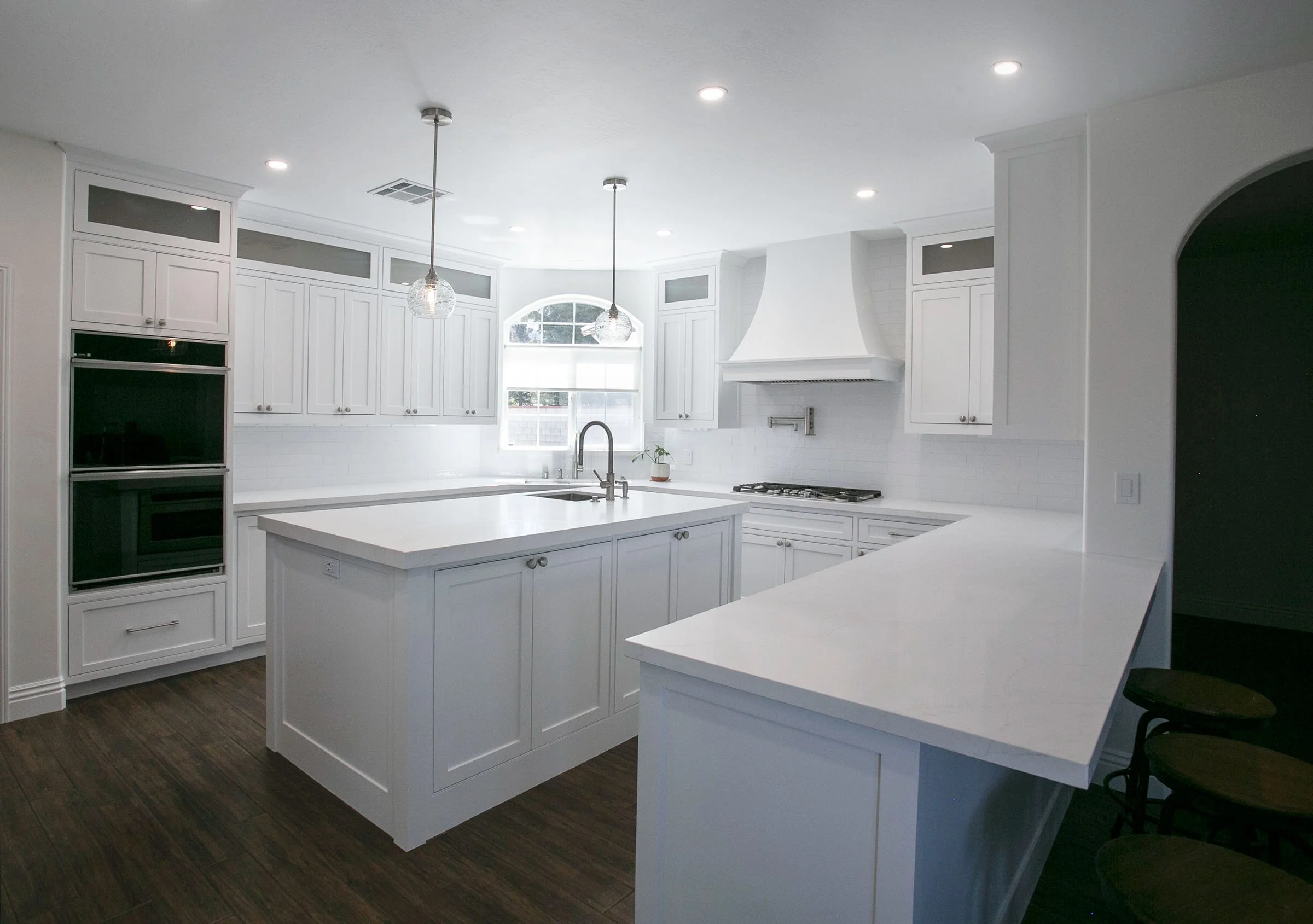 Custom white shaker kitchen cabinets with large island, quartz countertops, and range hood in Tehachapi, California