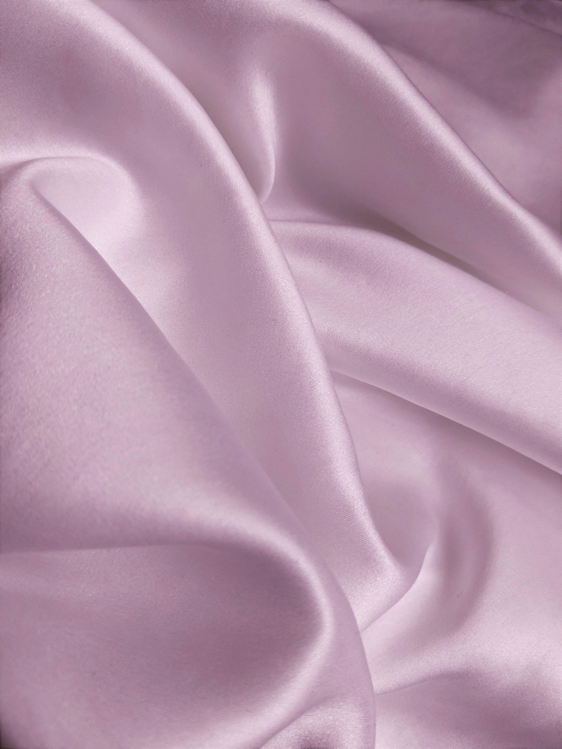 Light pink satin fabric with smooth, shiny surface and soft folds.