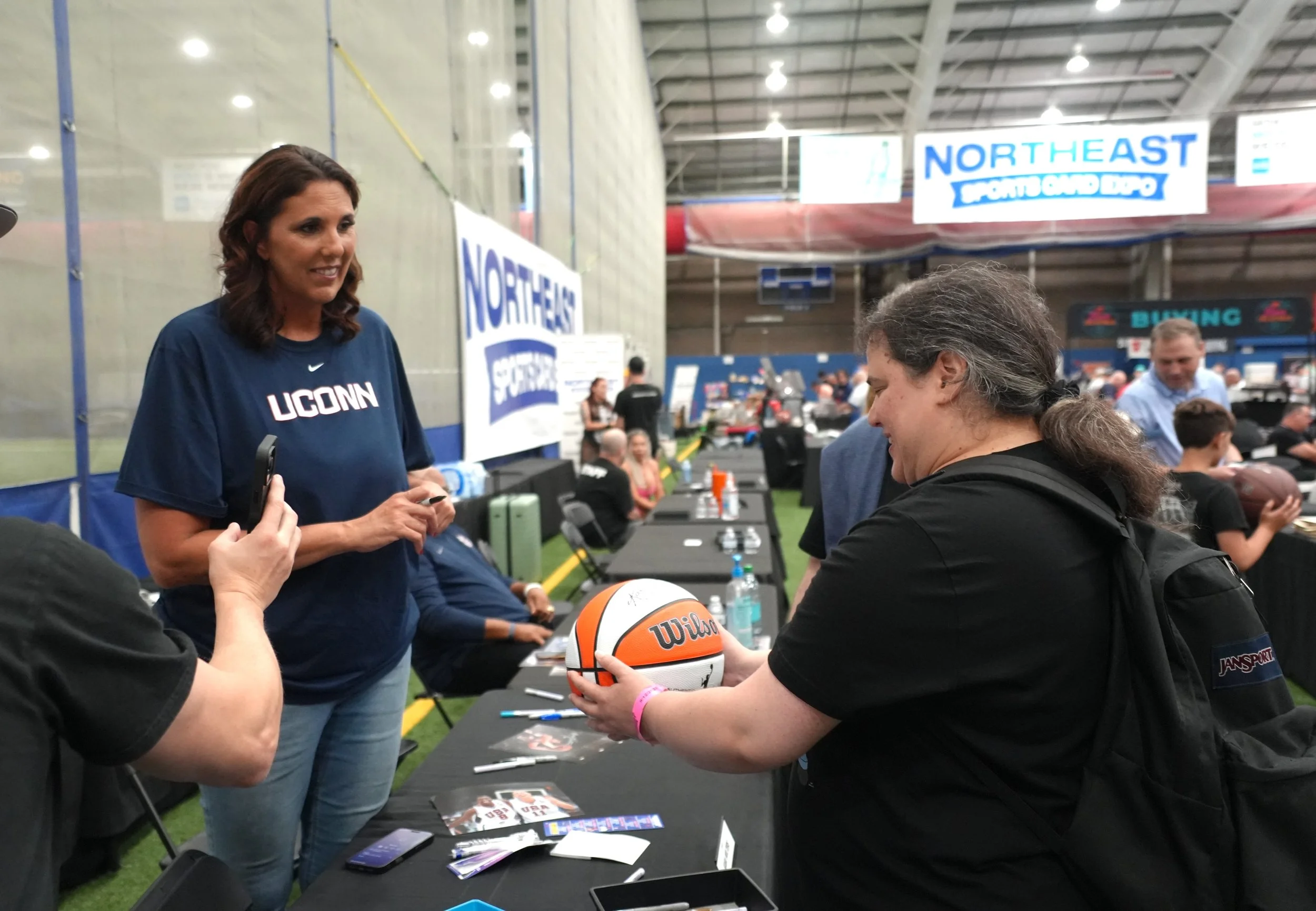 UConn legend Kara Wolters signs a basketball for a raffle prize winner