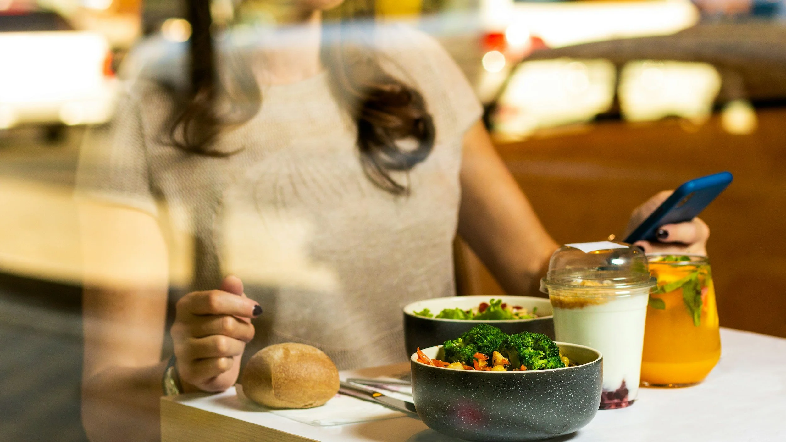Woman enjoying a balanced meal with vegetables and a whole-grain roll.
