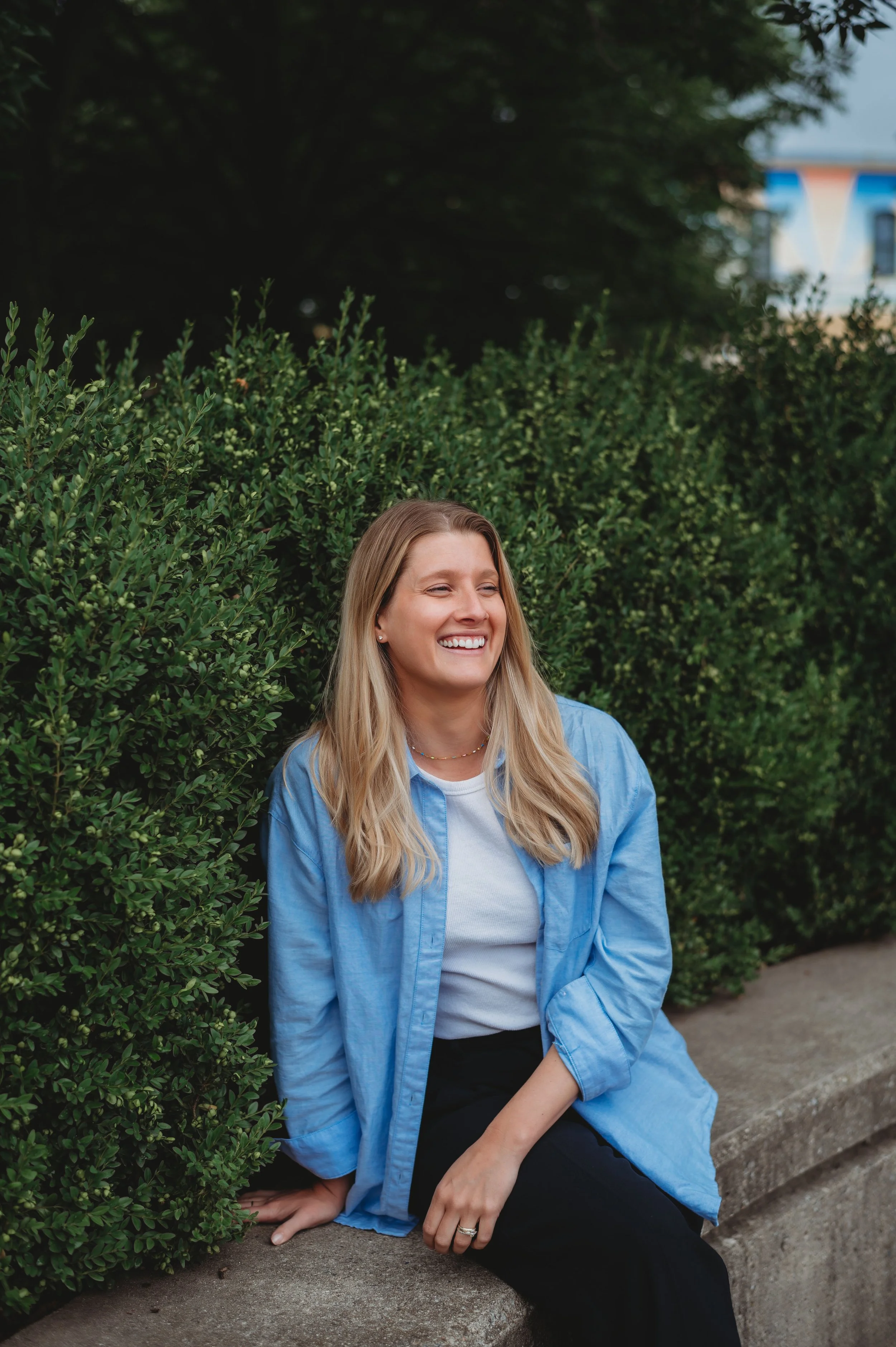 Carley Rollins, licensed nutritionist and board-certified health coach, smiling outdoors beside a green hedge.