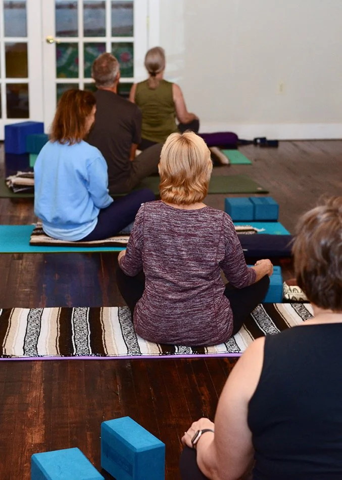 Beginner Yoga, Members doing yoga on yoga mats, yoga blocks, bolsters, personal props and provided by the studio.