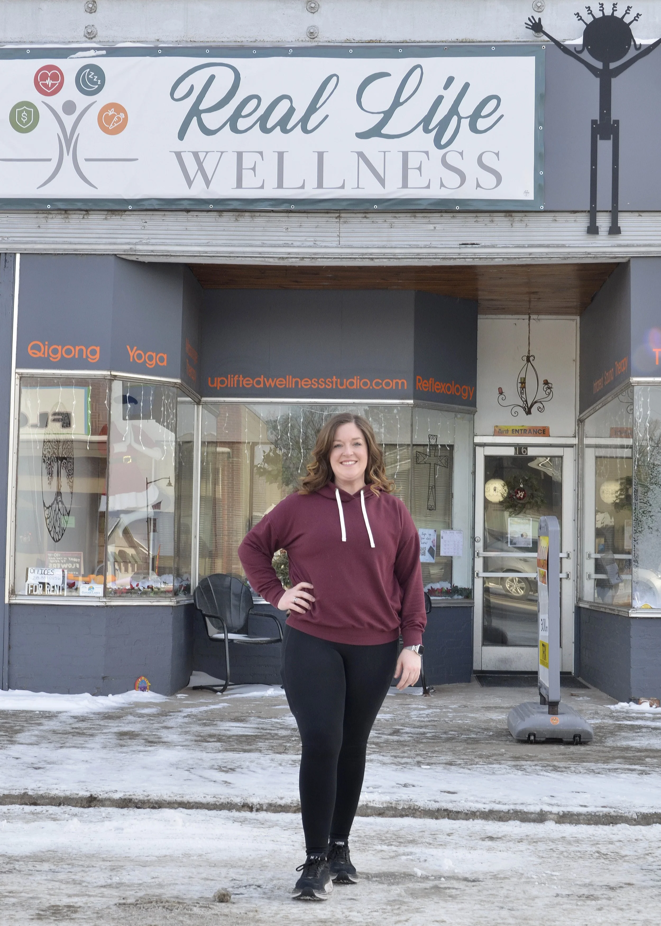 Professional photo of Real Life Wellness Studio owner, Bailey Swensen in front of studio building on Main Street in Crosby.