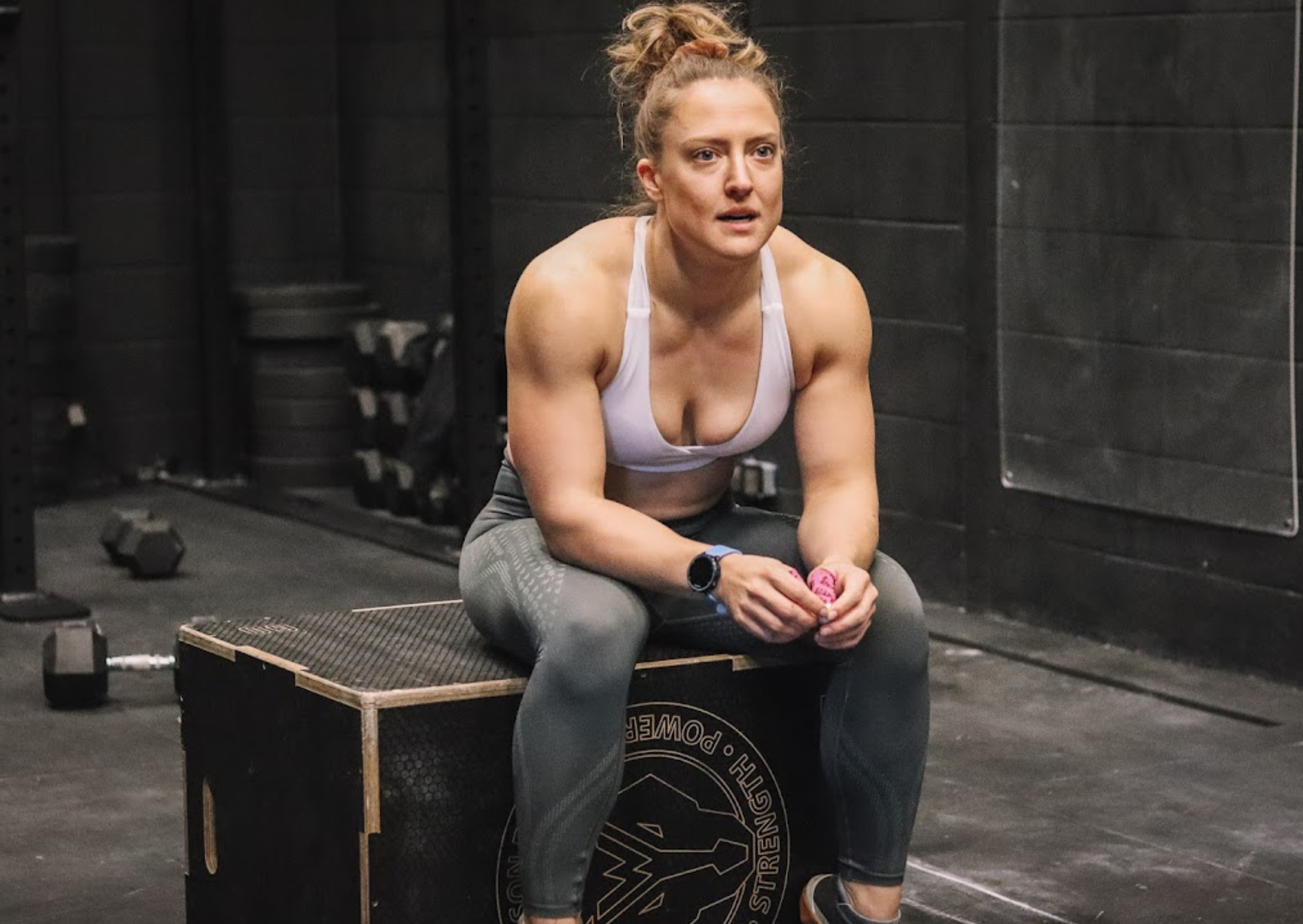 a woman in a white sports bra sat on a box after a workout
