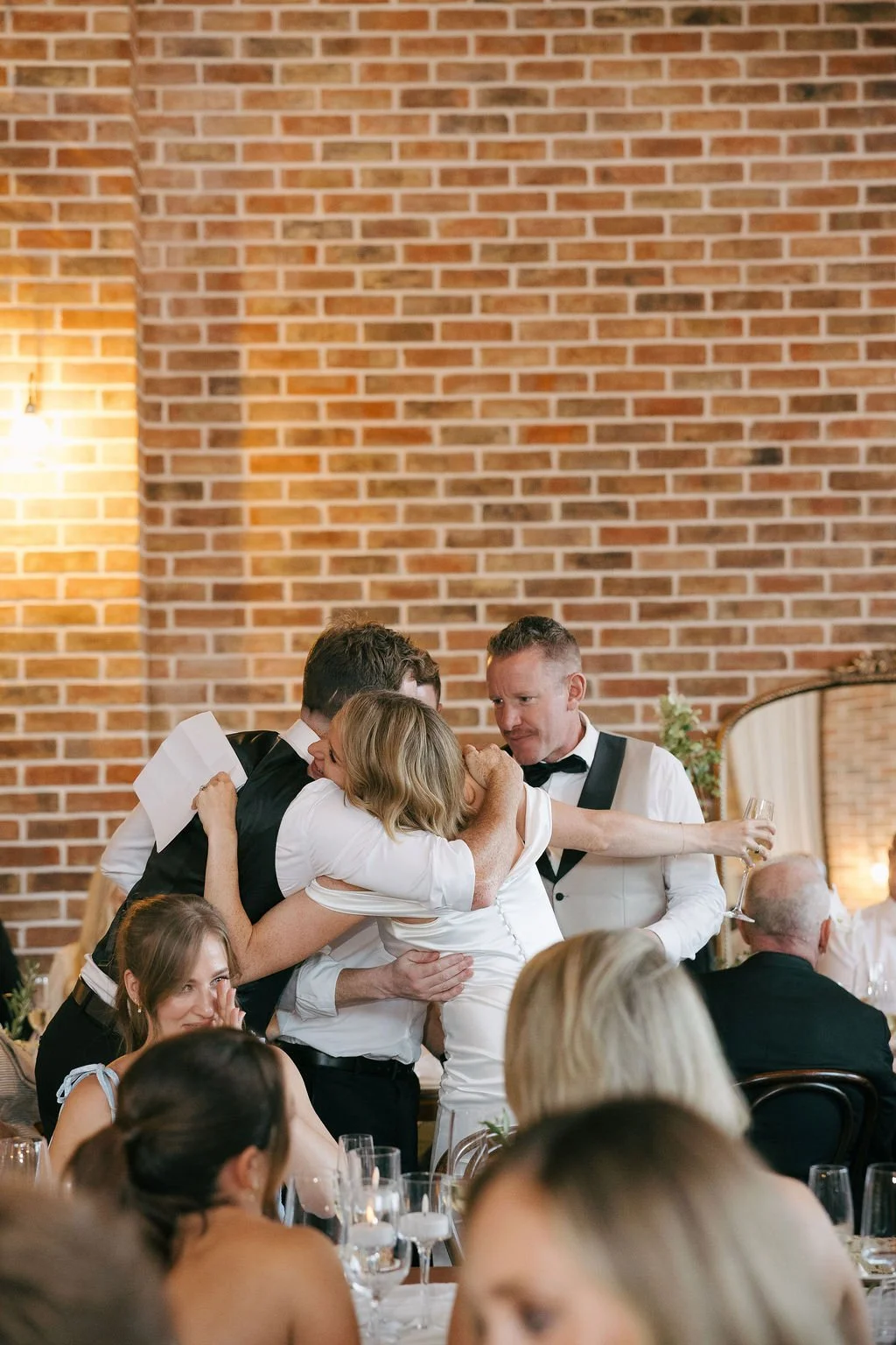 Bride hugging brothers at her wedding 