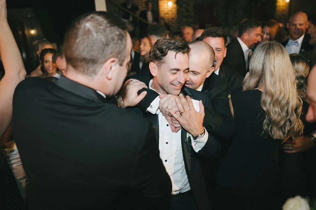 Groom on dance floor dancing with friends 