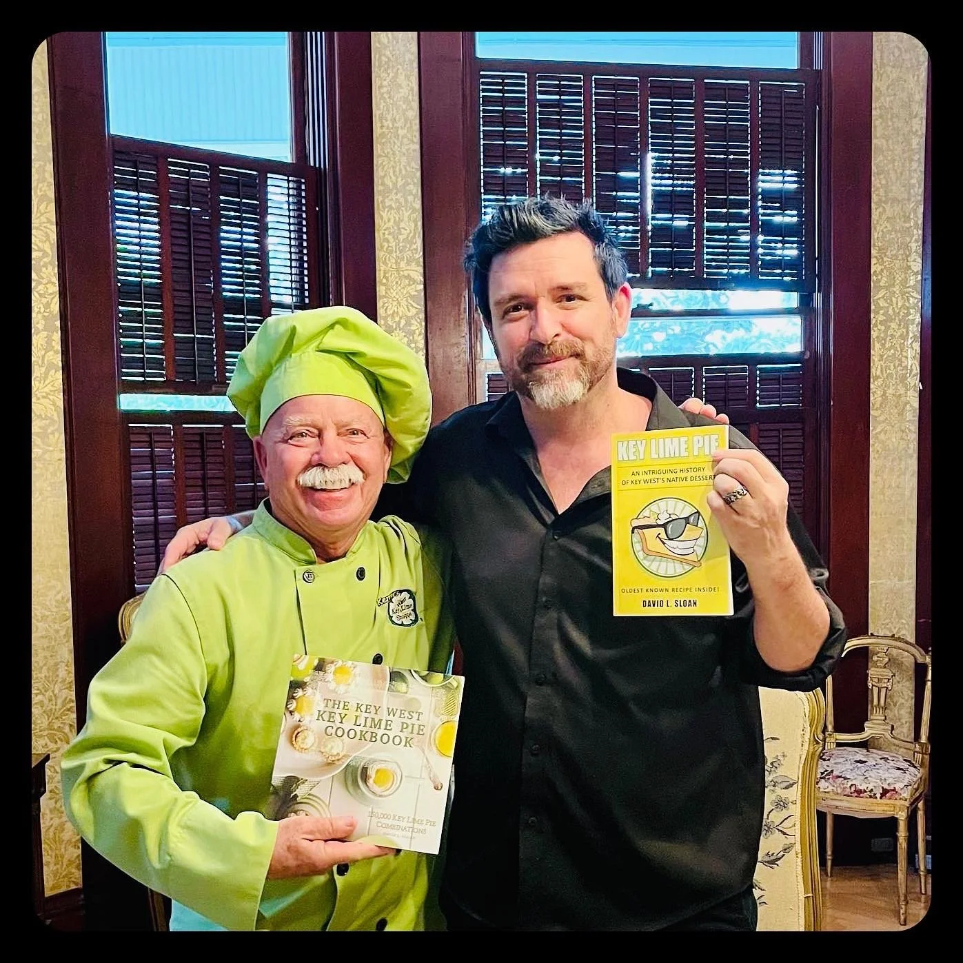 Key Lime Pie legends Kermit Carpenter and David Sloan are holding books titled "The Key West Key Lime Pie Cookbook," and "Key Lime Pie". Both are smiling.