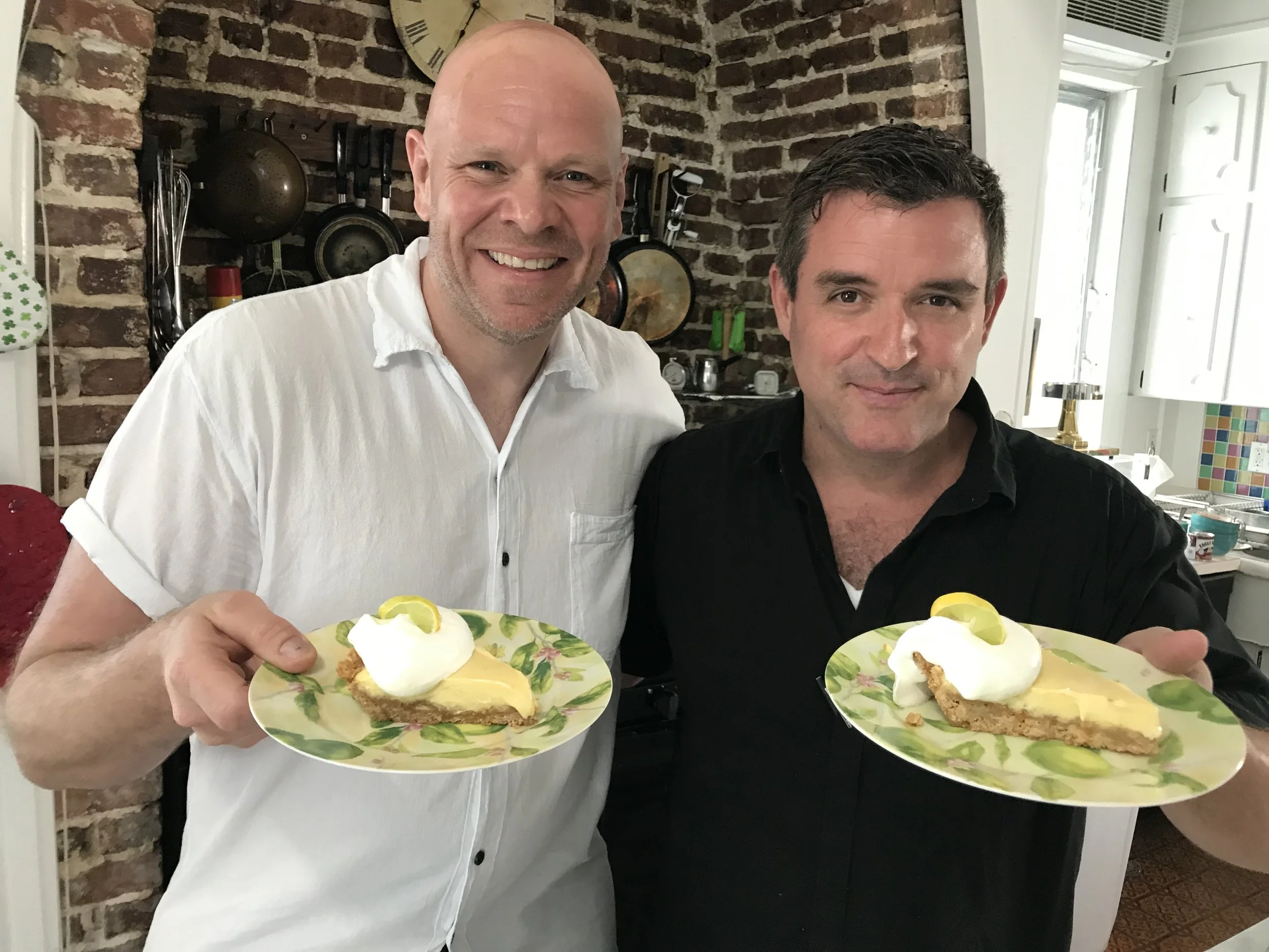 Chefs David Sloan and Tom Kerridge smile as they hold plates of Key lime pie with whipped cream in a Key West kitchen.