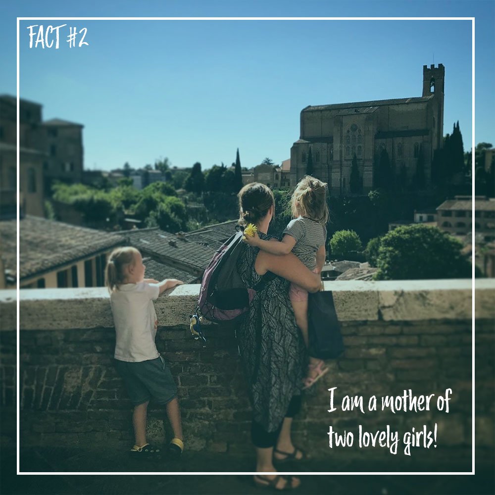 Mother with two young girls overlooking a cityscape with a large church or cathedral in the background, on a sunny day. Text overlay reads 'FACT #2' and 'I am a mother of two lovely girls!'.