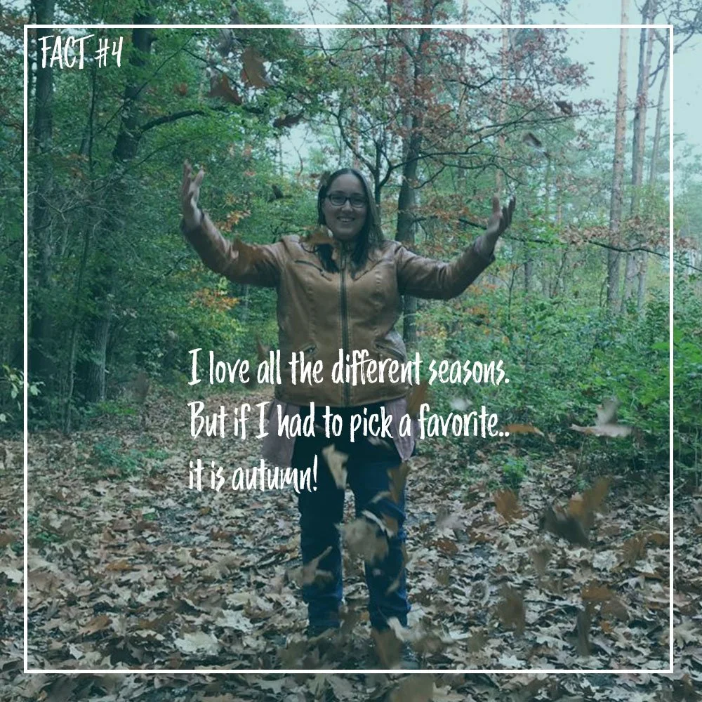 A woman standing in a forest during autumn, surrounded by falling leaves, smiling with arms raised. Overlaid text reads: 'Fact #4: I love all the different seasons, but if I had to pick a favorite... it is autumn!'