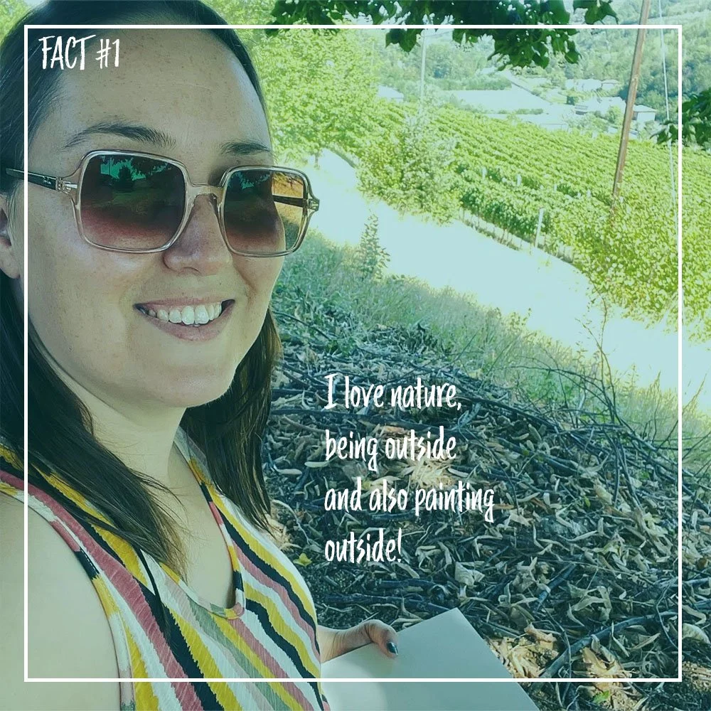 A woman wearing sunglasses smiling outdoors with trees and bushes in the background, holding a sketchpad. Overlaid text says, "Fact #1: I love nature, being outside and also painting outside!"