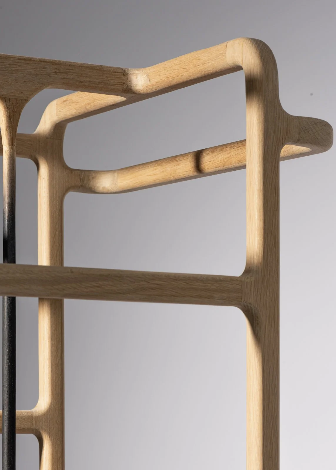 Structure en bois avec courbes et espaces ouverts, avec un fond gris clair.