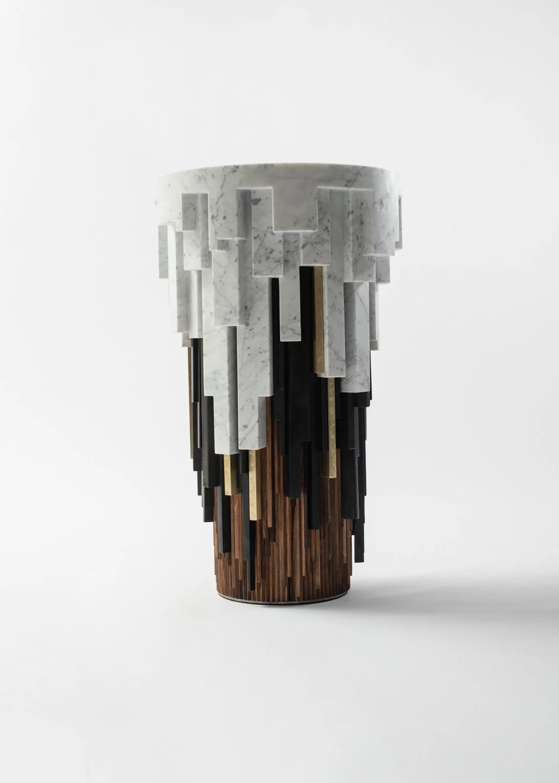 Une sculpture moderne composée de blocs en marbre blanc, bois et métal, formant une structure verticale.