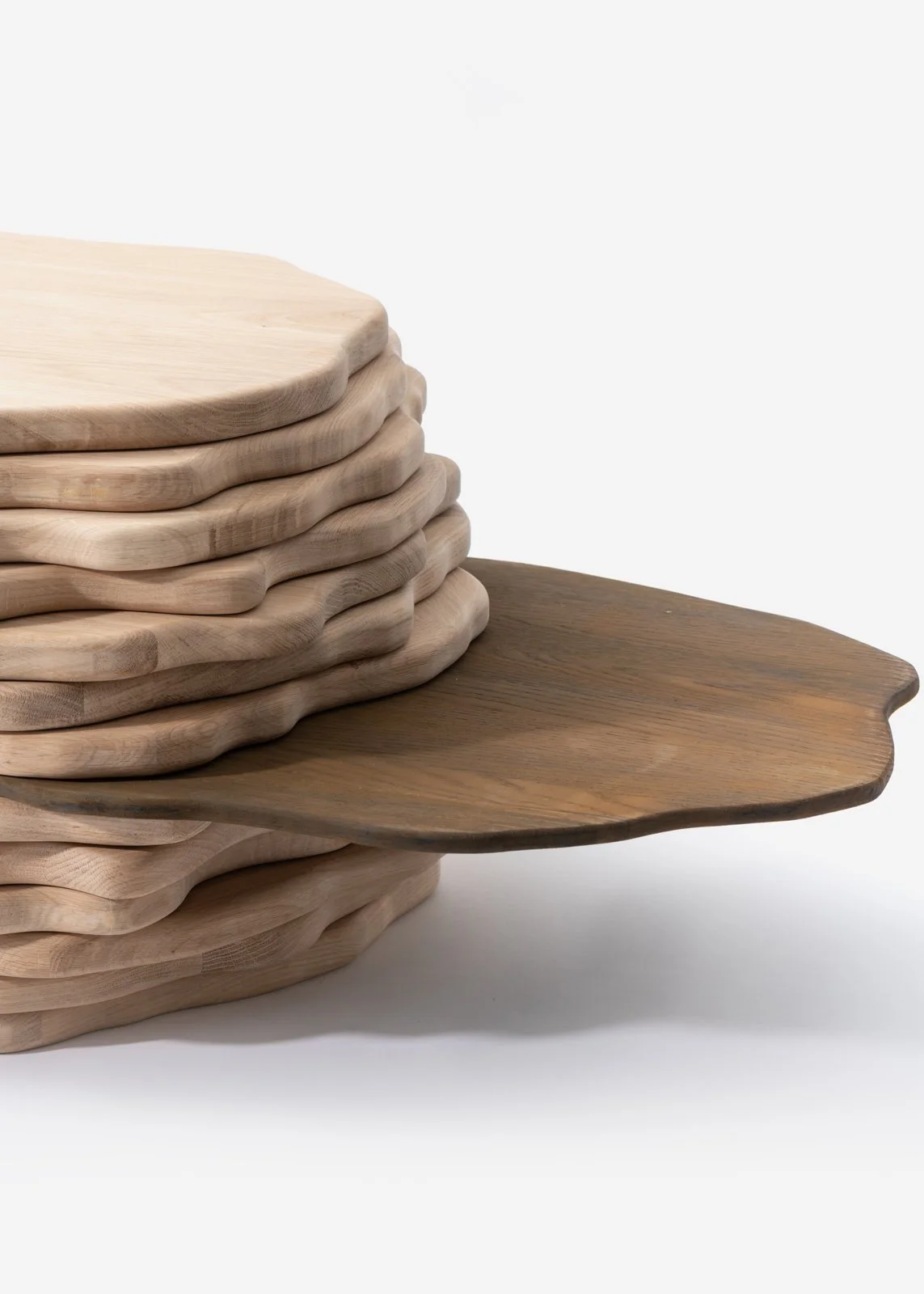 Une pile de planches en bois de différentes formes et couleurs sur fond blanc.