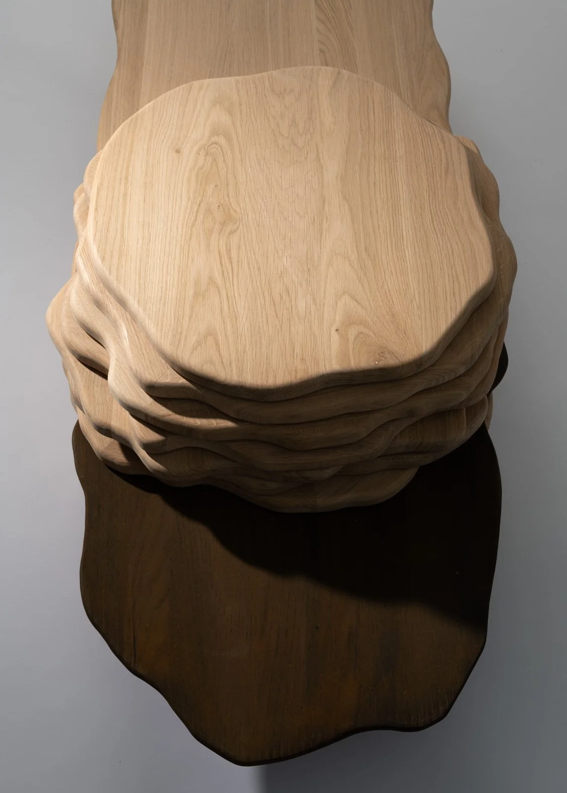 Pile de sept planches en bois naturel, de formes arrondies et irrégulières, posées l'une sur l'autre