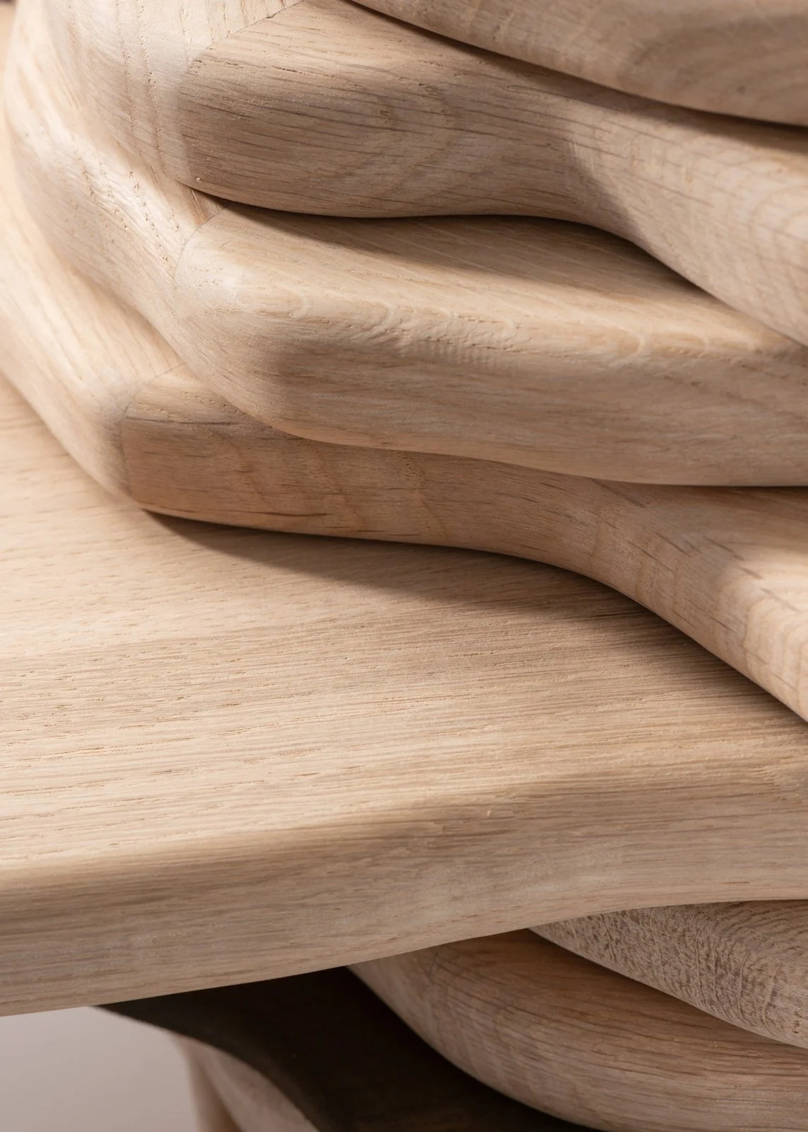 Gros plan de plusieurs planches de bois naturelles, empilées et courbées, avec une texture visible et une finition lisse.