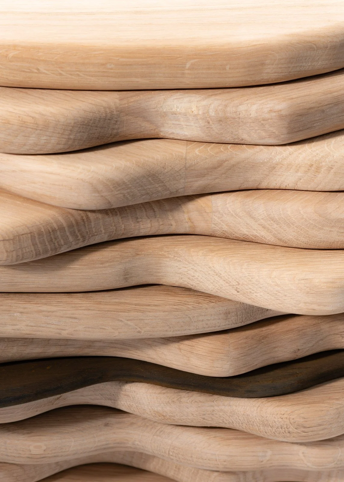 Pile de planches ou d'éléments en bois, avec des formes courbes et des couleurs naturelles de bois clair et foncé.