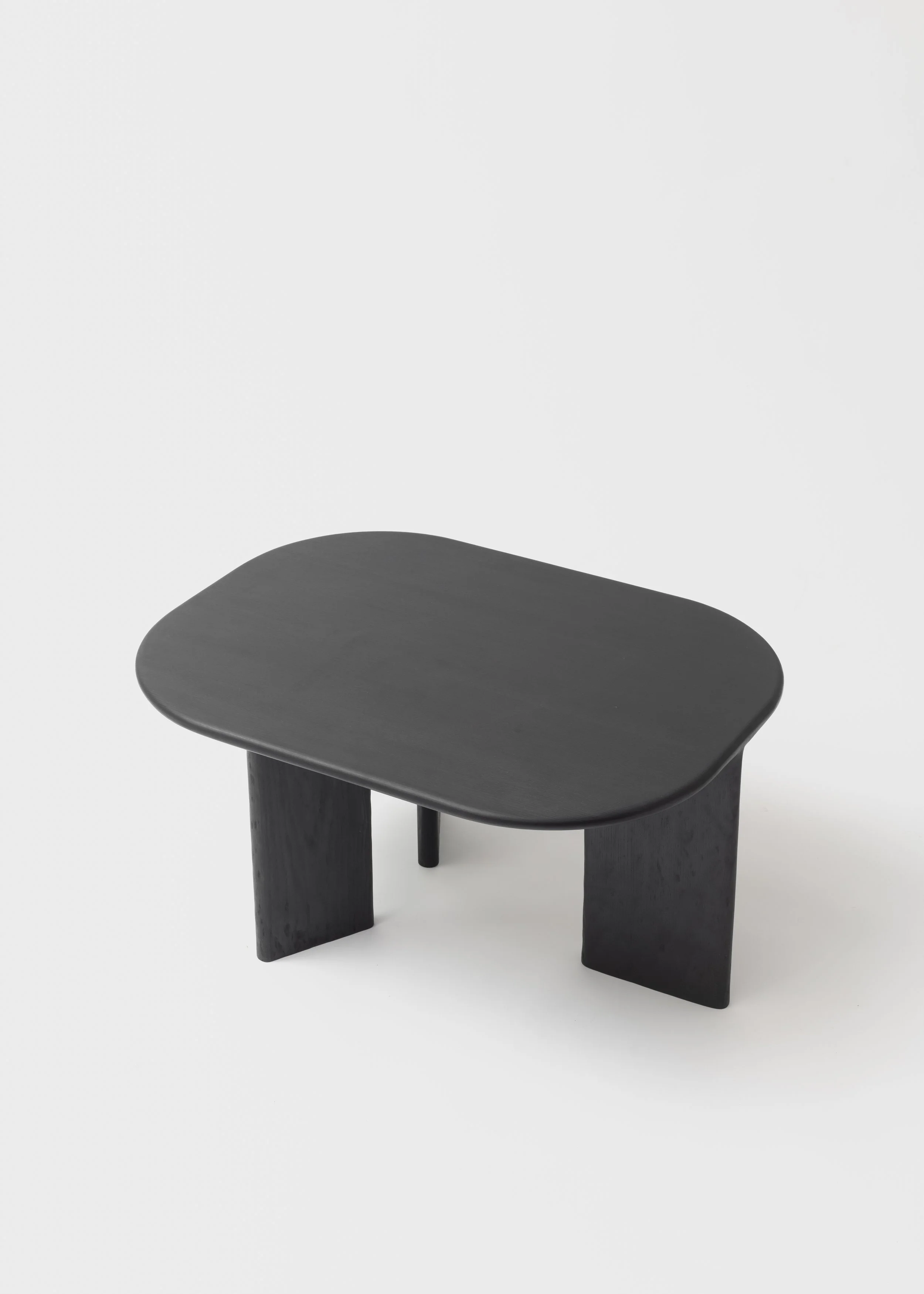 Table basse noire avec un plateau rectangulaire aux coins arrondis et deux jambes épaisses