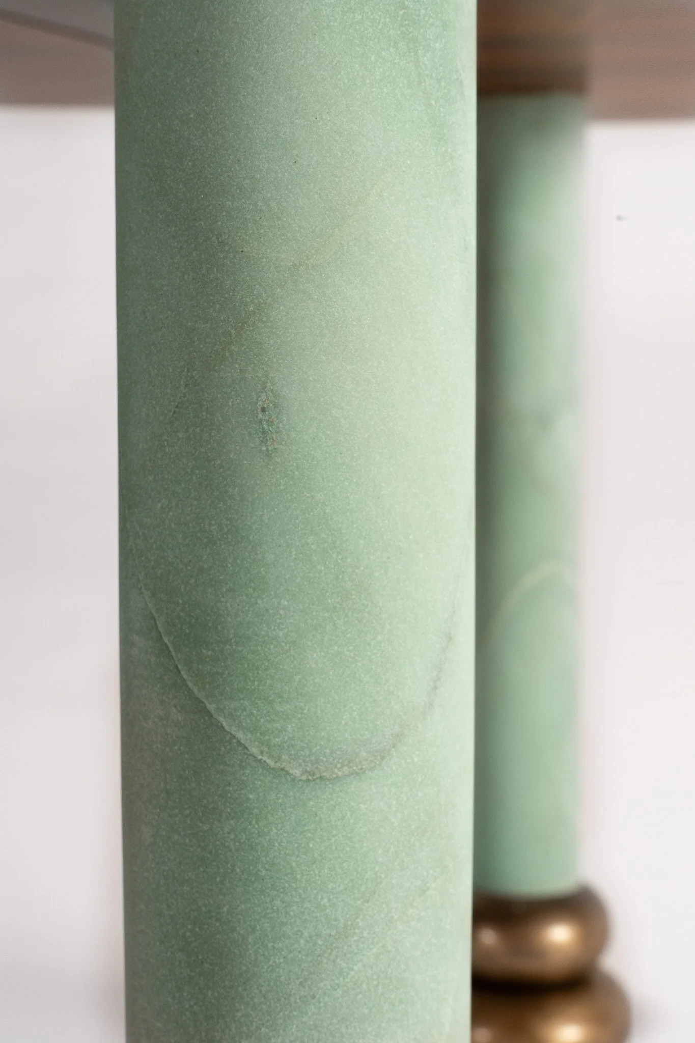Deux cylindres en bois peint en vert, avec un support métallique en bronze à leur base, vue en gros plan.