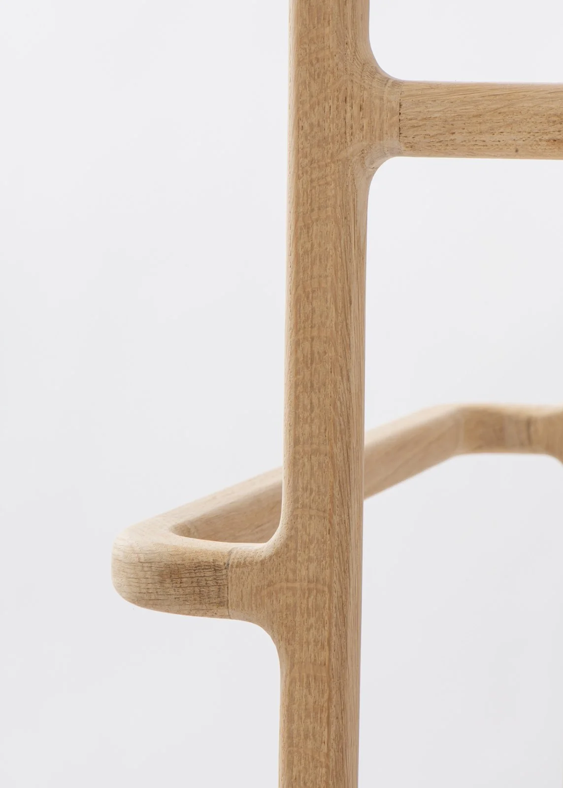 Détail d'une structure en bois clair, peut-être un meuble ou un support, contre un fond blanc.