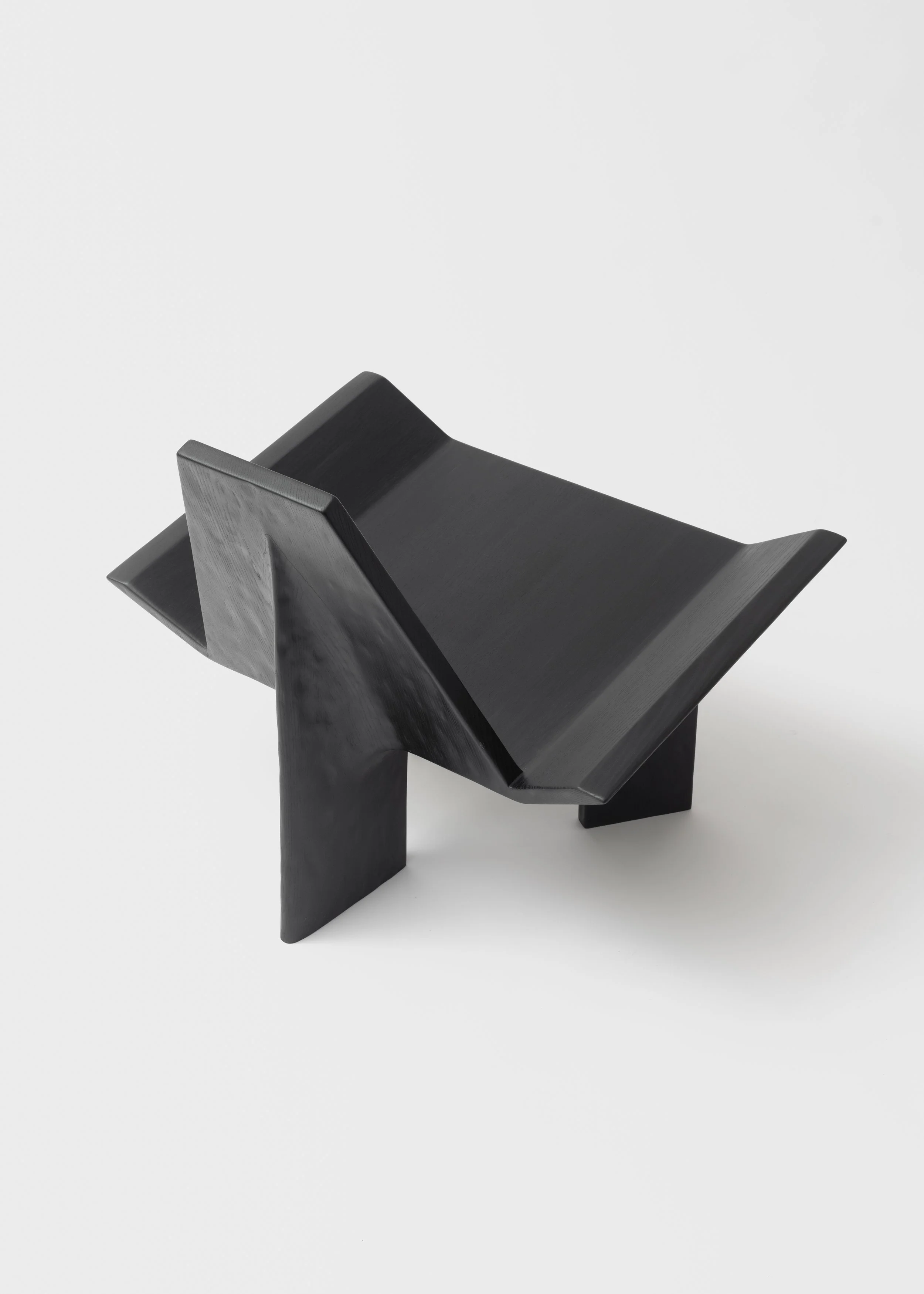 Une petite chaise noire en bois avec un design moderne, posée sur un fond blanc.