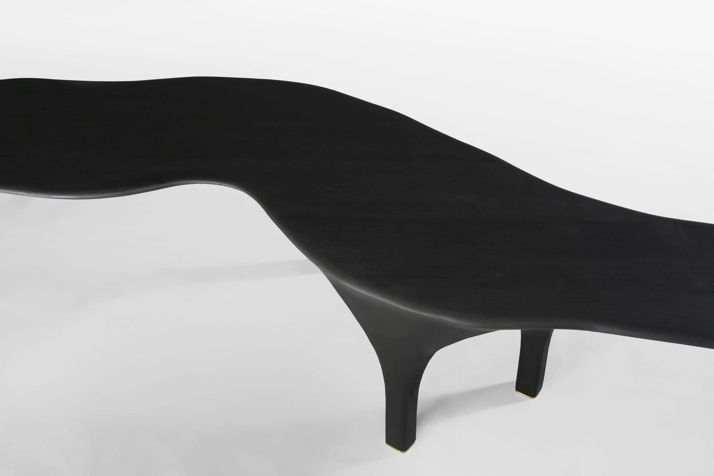 Une table noire en bois avec des pieds courbés, vue de dessus, sur un fond blanc.