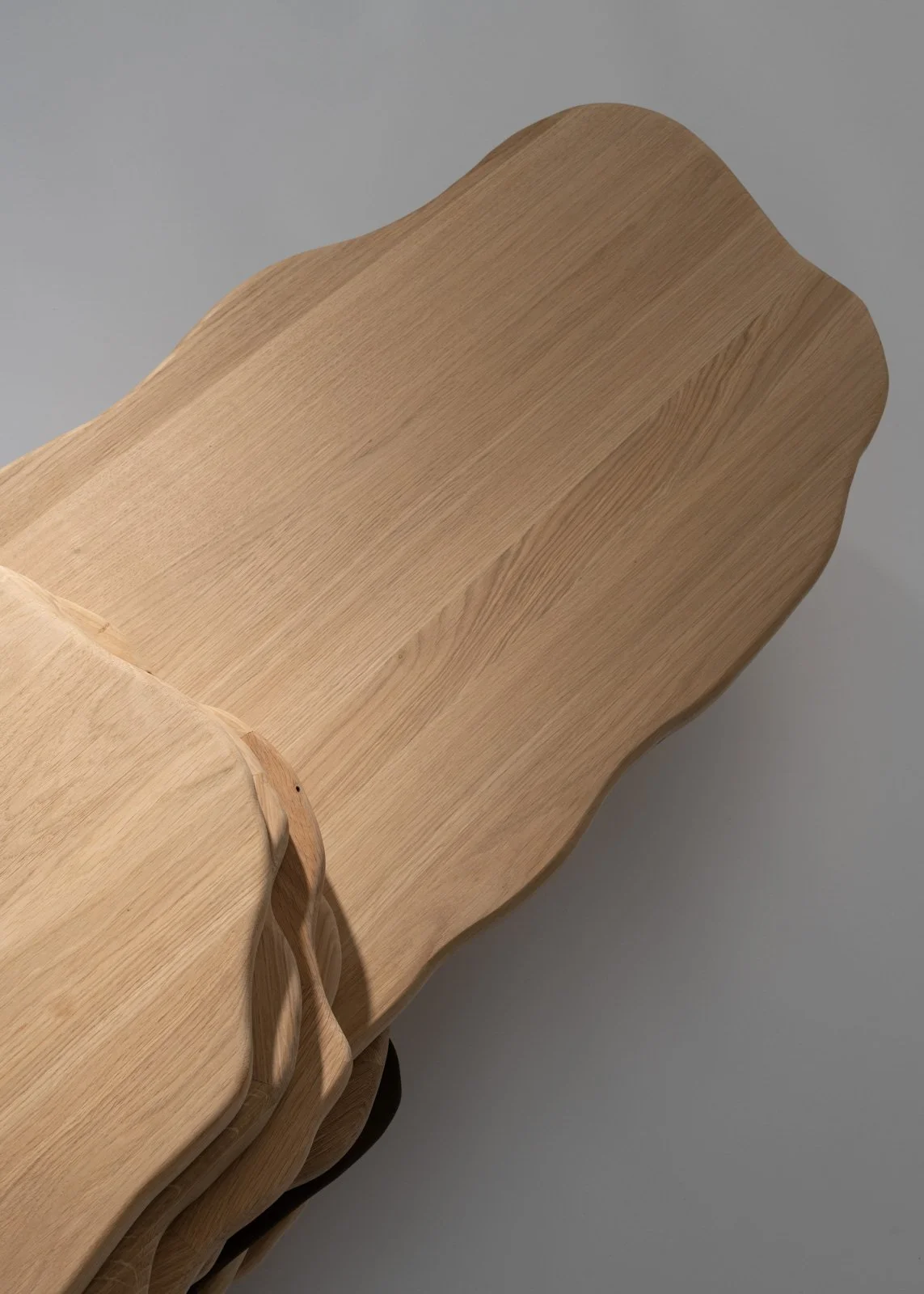 Gros plan d'une pièce de mobilier en bois clair avec un motif ondulé et des bords arrondis.