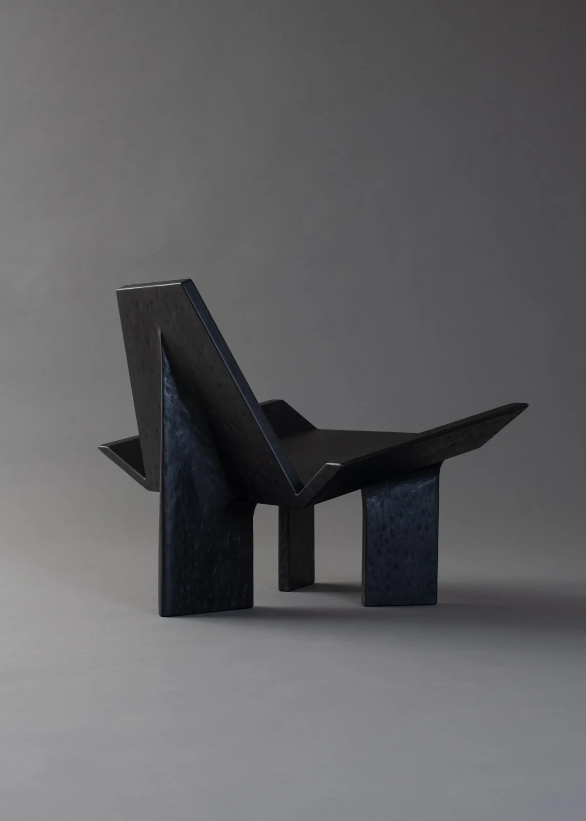 Chaise en bois noir moderne avec un design angulaire sur un fond gris