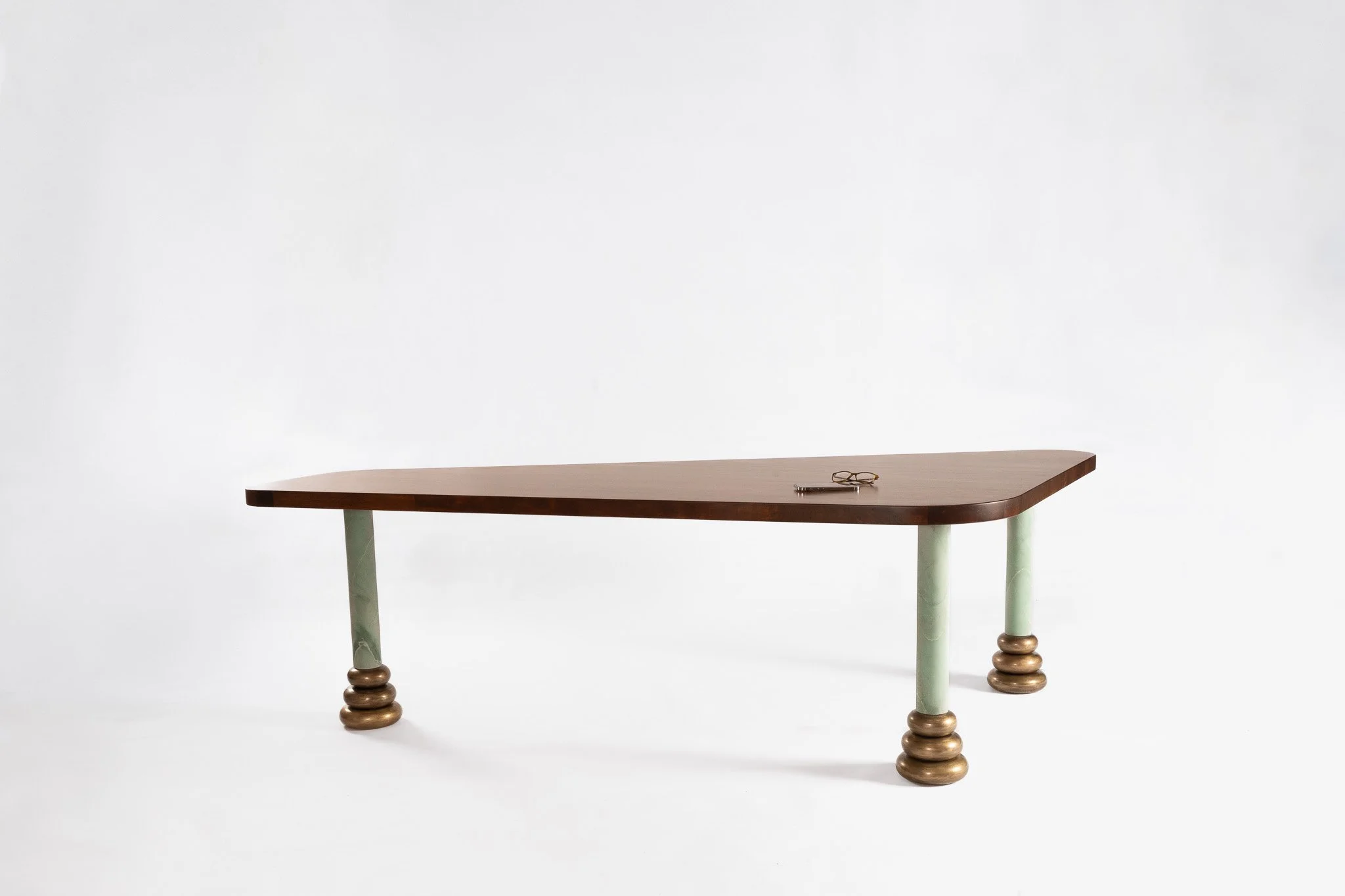 Table en bois avec trois jambes peintes en vert, chaque jambe ayant des cercles en bois. Sur la table, il y a une paire de lunettes.