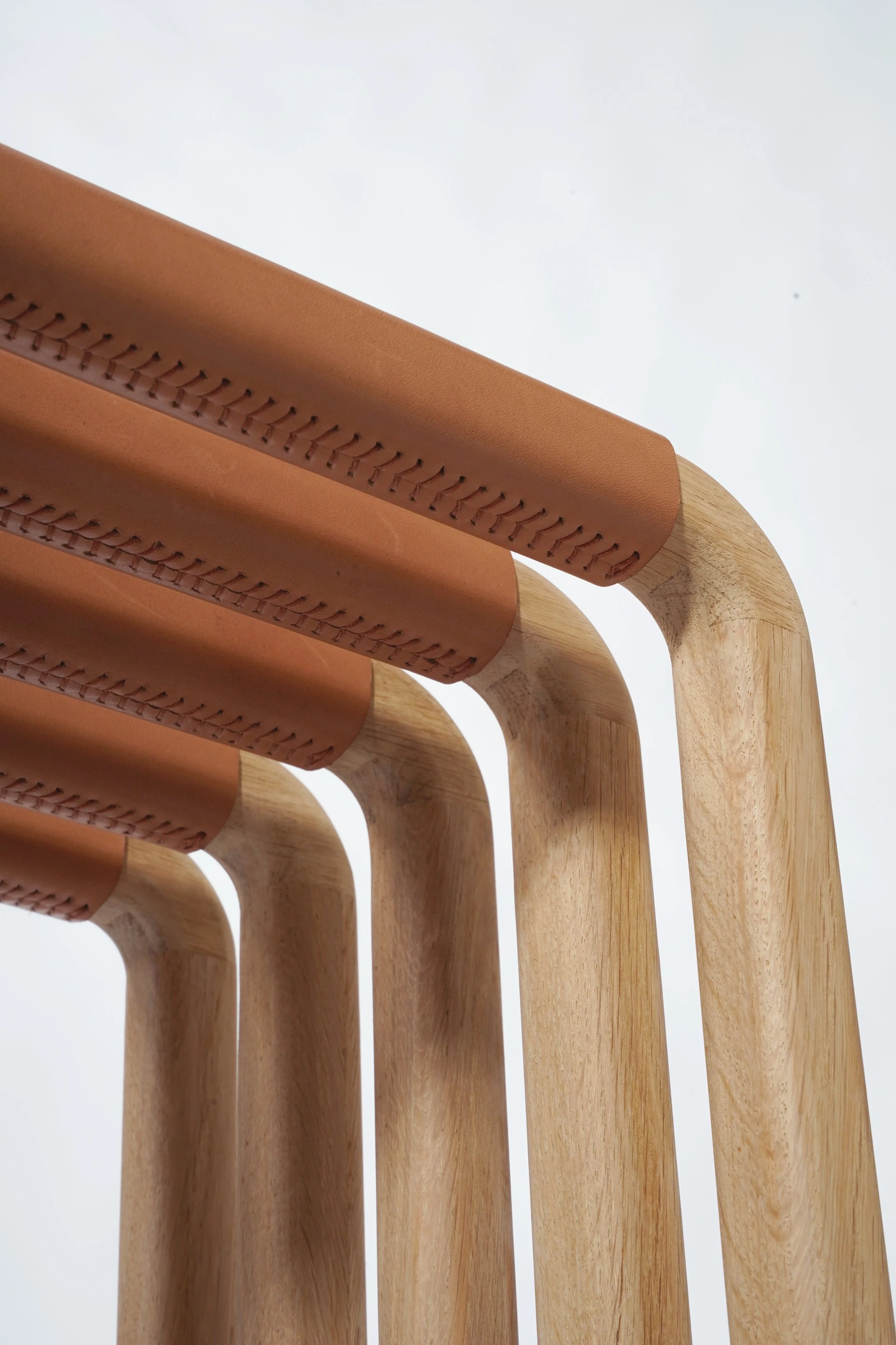 Gros plan d'un meuble en bois avec des éléments en cuir marron, montrant la structure en bois clair et le détail des coutures du cuir.