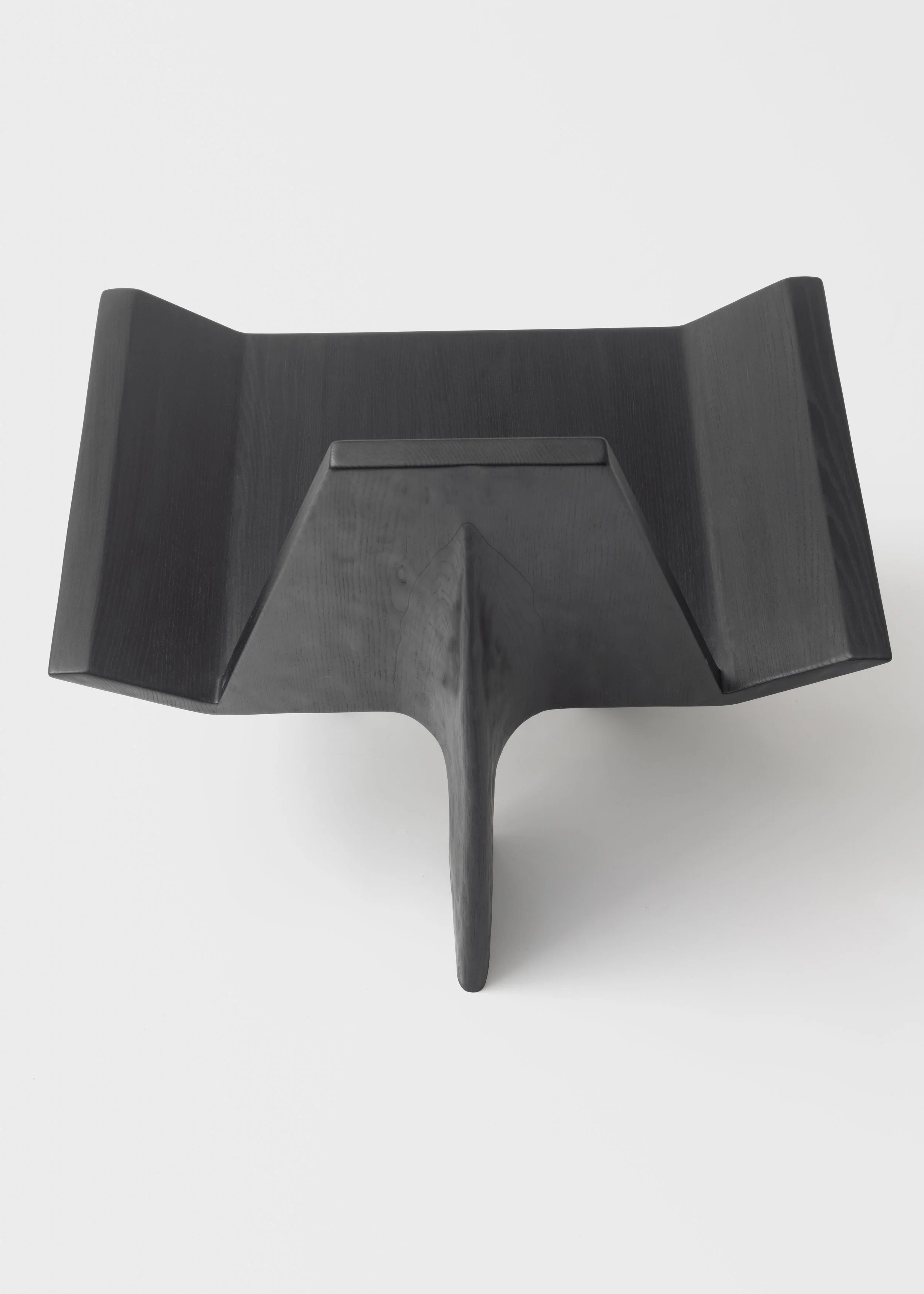 Une sculpture en bois noir avec une base triangulaire et une extension centrale verticale, vue de dessus.