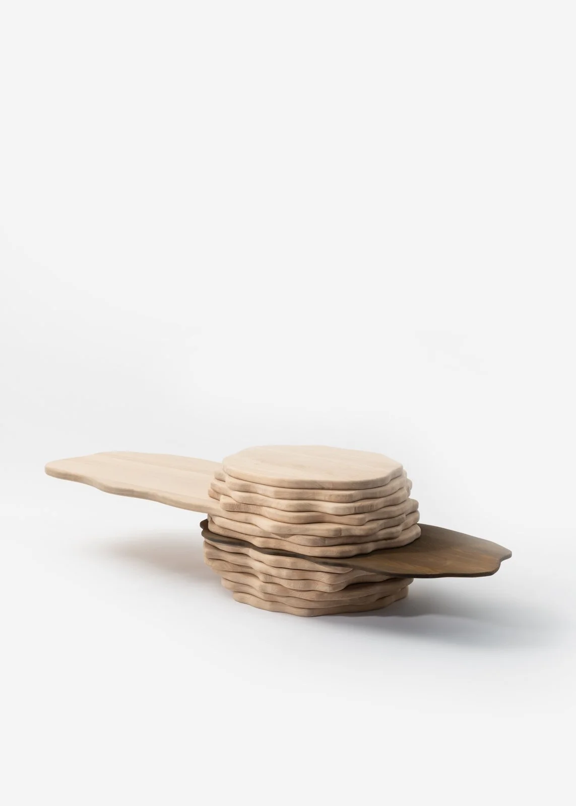 Une sculpture en bois composée de plusieurs planches plates et irrégulières empilées, formant une structure artistique.