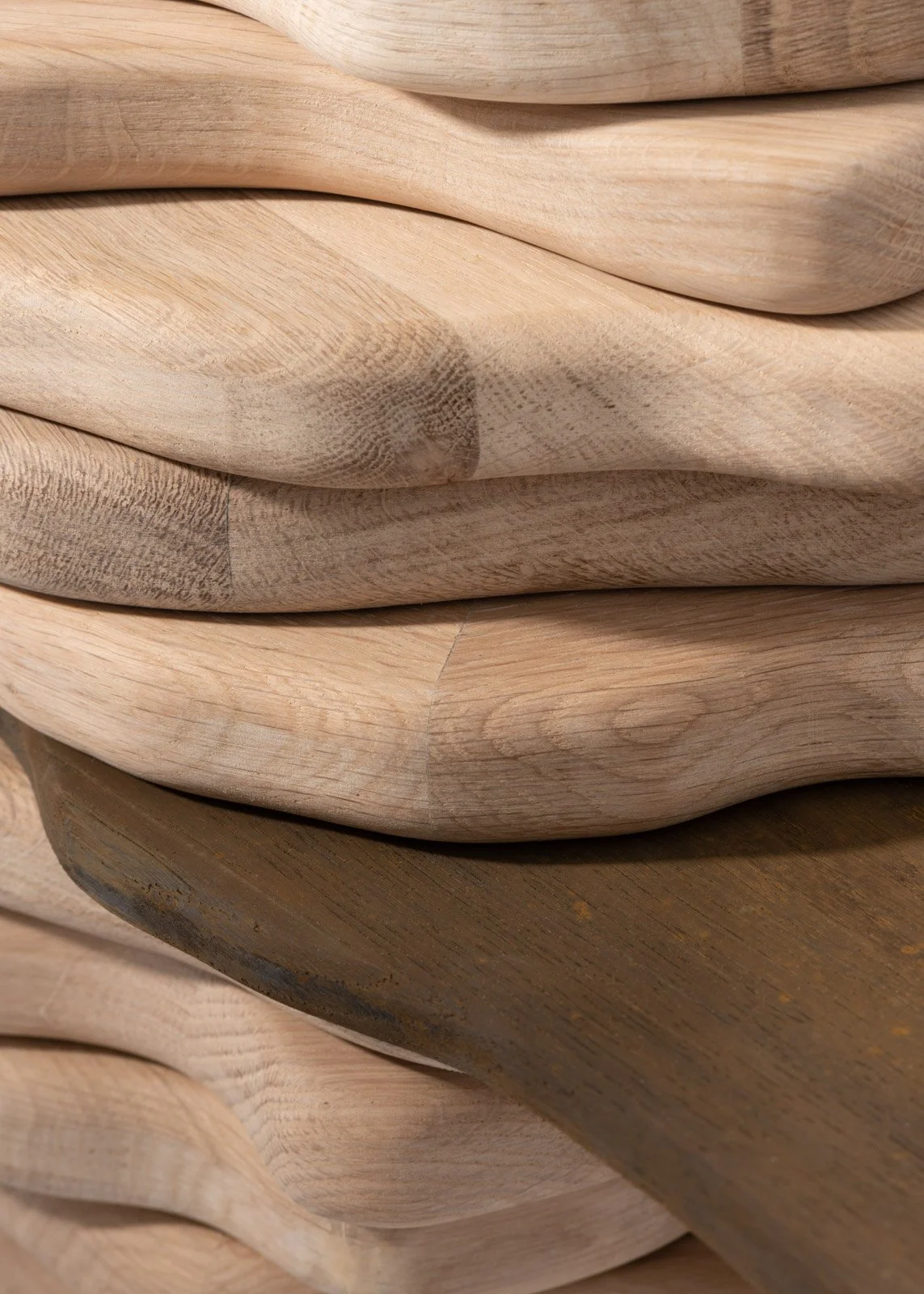 Gros plan de plusieurs planches de bois empilées, certaines en bois clair, une en bois plus foncé.