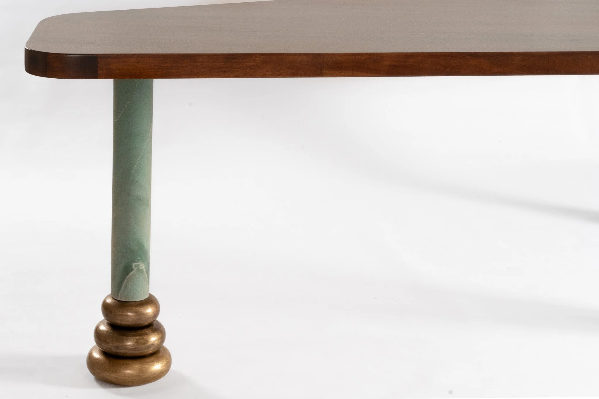 Pied de table en bois avec une jambe en marbre vert et une base en forme de trois anneaux dorés.