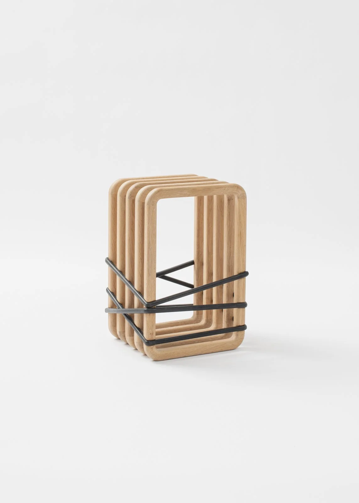 Un ensemble de quatre objets en bois de forme rectangulaire, empilés et maintenus ensemble par des bandes élastiques noires.