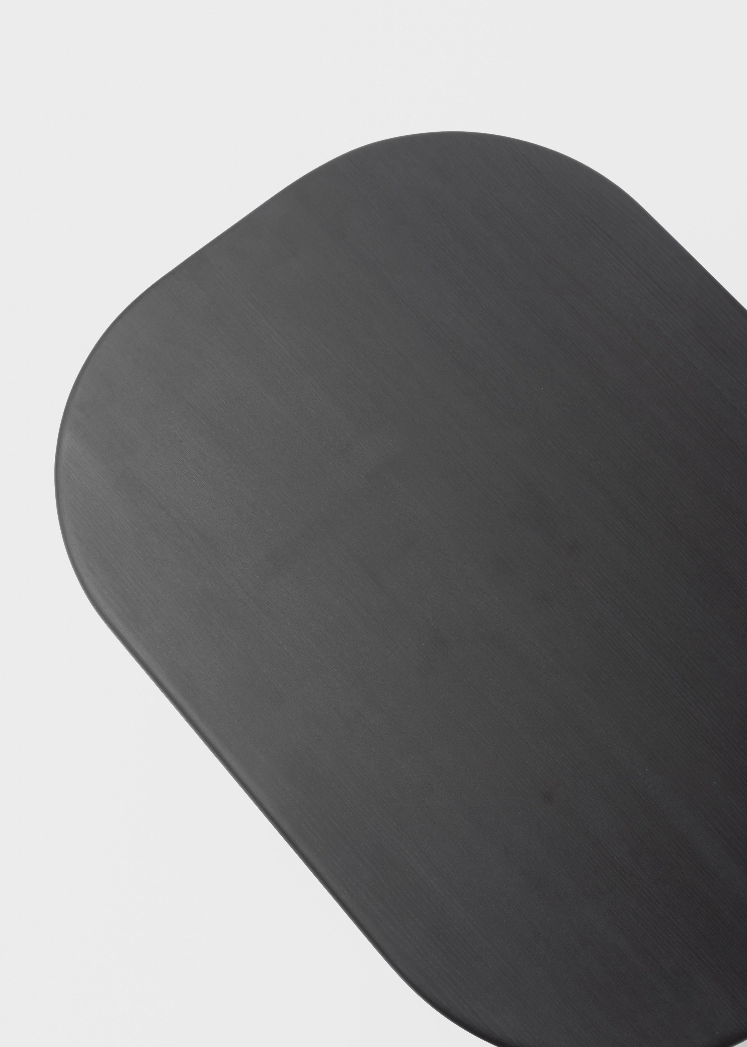 Surface en bois sombre agrandie, avec une forme arrondie, vue en gros plan sur fond blanc.