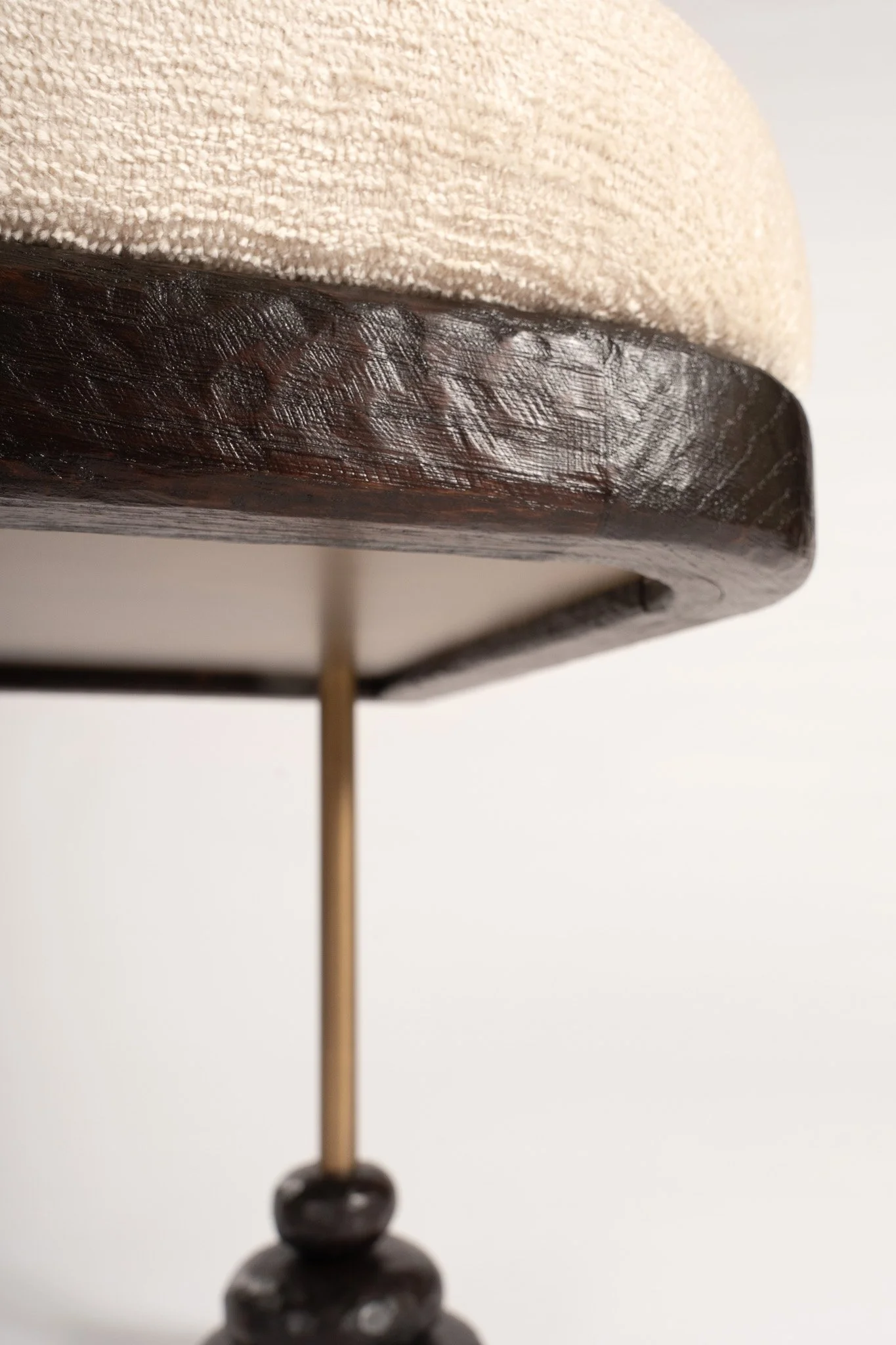 Zoom sur le dessous d'une lampe avec un abat-jour en tissu beige et une base en bois sombre.